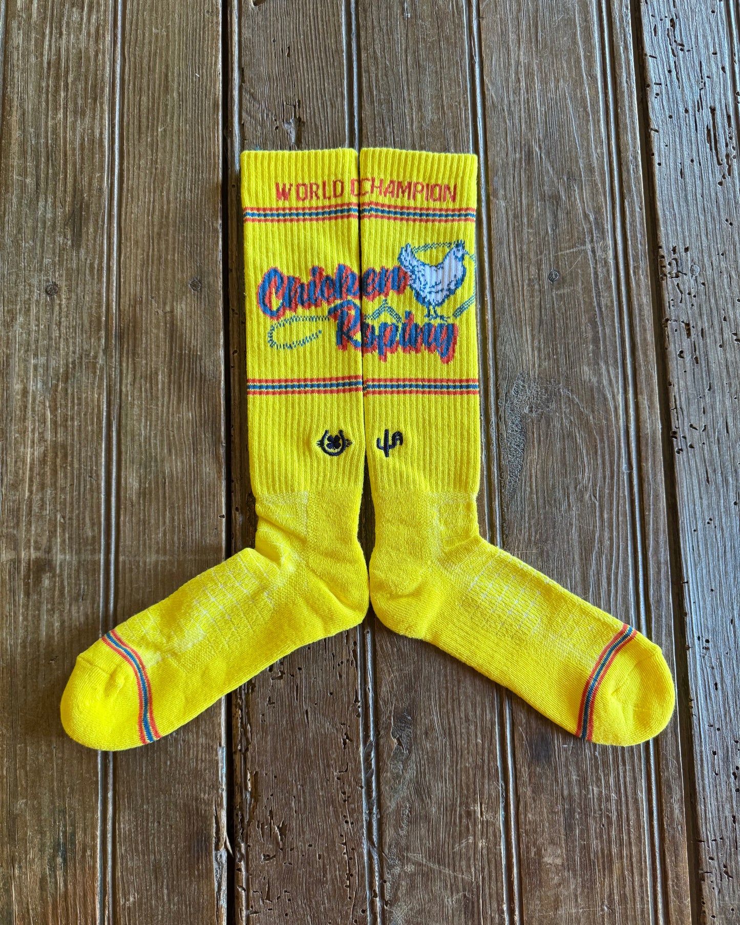 Cactus Alley Chicken Roping Performance Socks in yellow showing design on rustic wood background