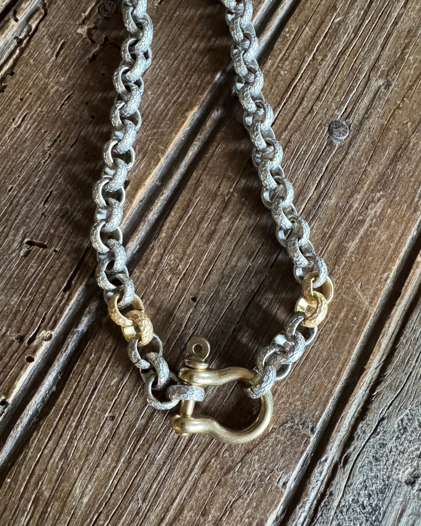Mixed metal shackle necklace on rustic wood background