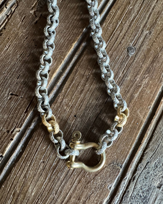 Mixed metal shackle necklace on rustic wood background