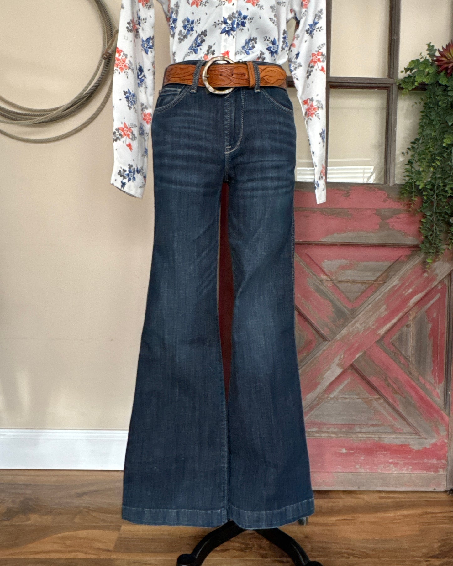 Blue jeans with a brown belt on a wooden floor.