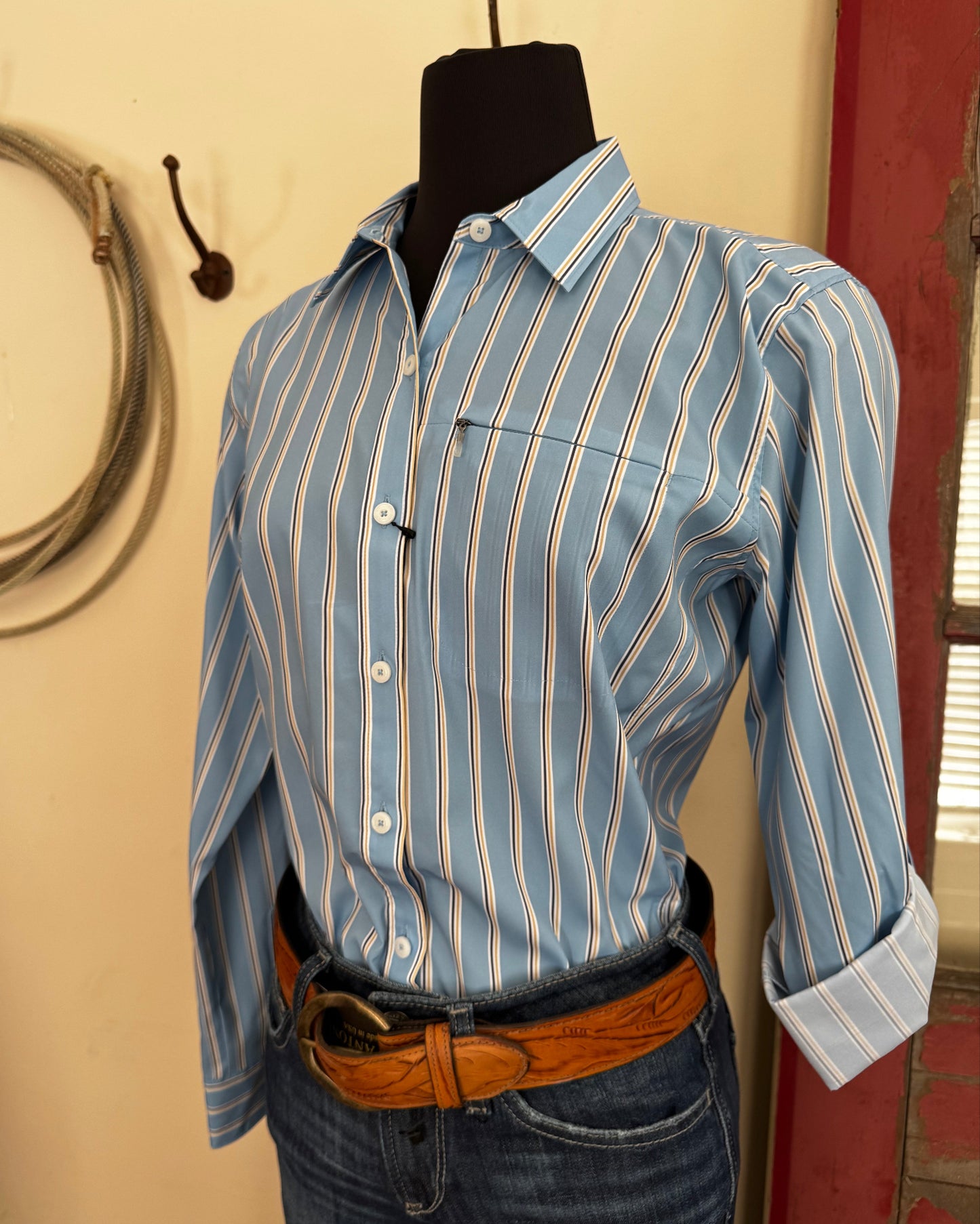 Person wearing a blue striped shirt and jeans with a belt, standing on a beige floor.