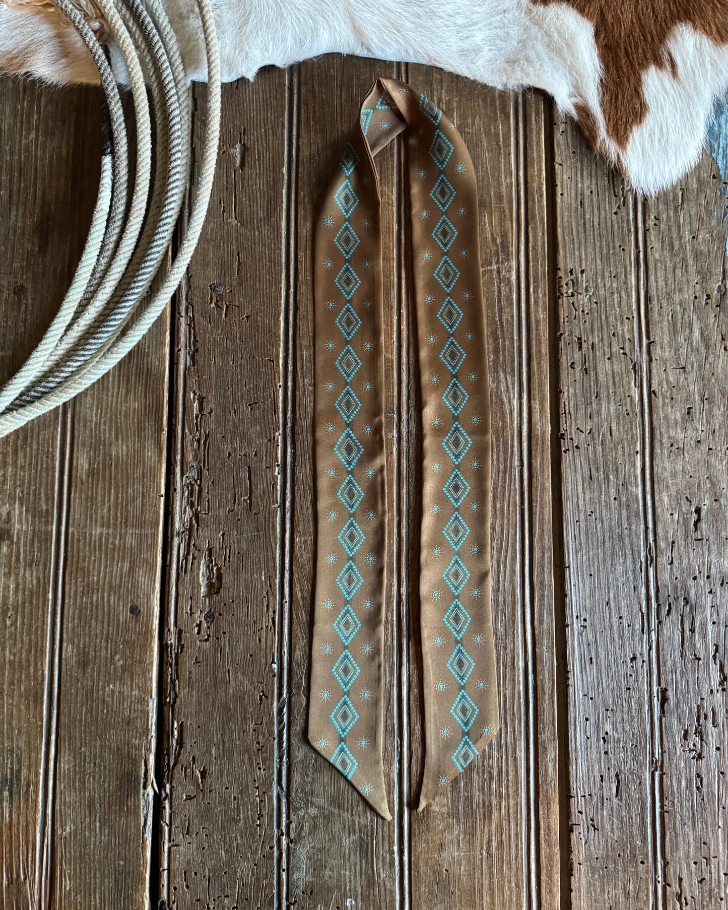 Ribbon scarf with geometric patterns on a wooden surface.