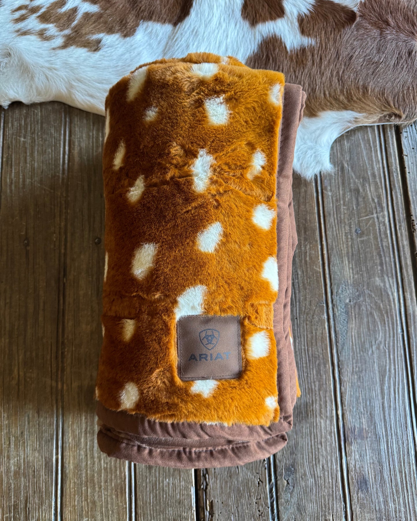 Folded blanket with brown and white pattern on a wooden surface
