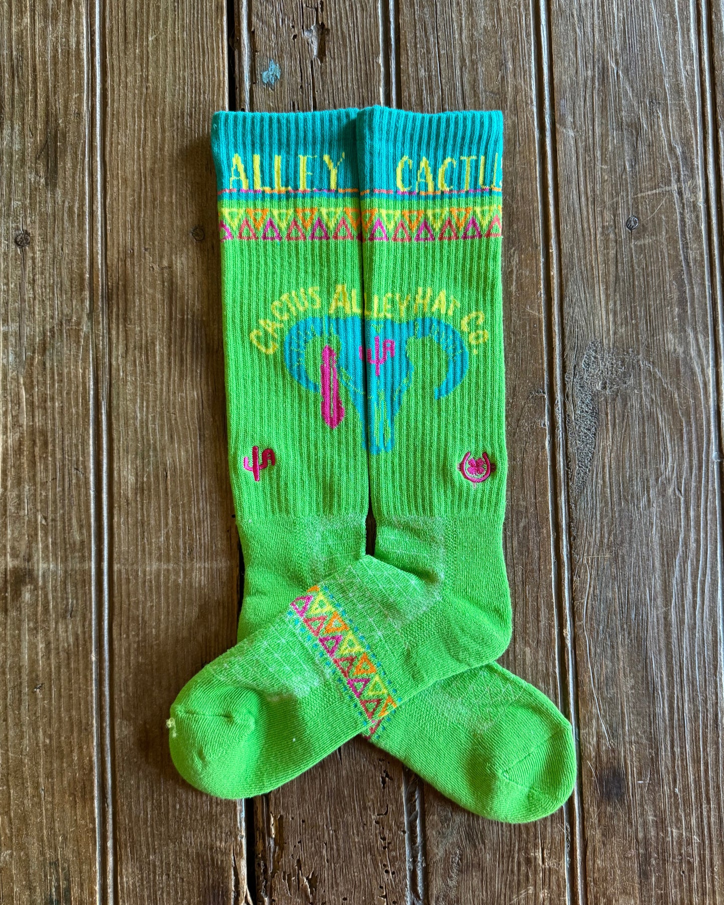 Cactus Alley Southwest Green Performance Socks showing design on rustic wood background