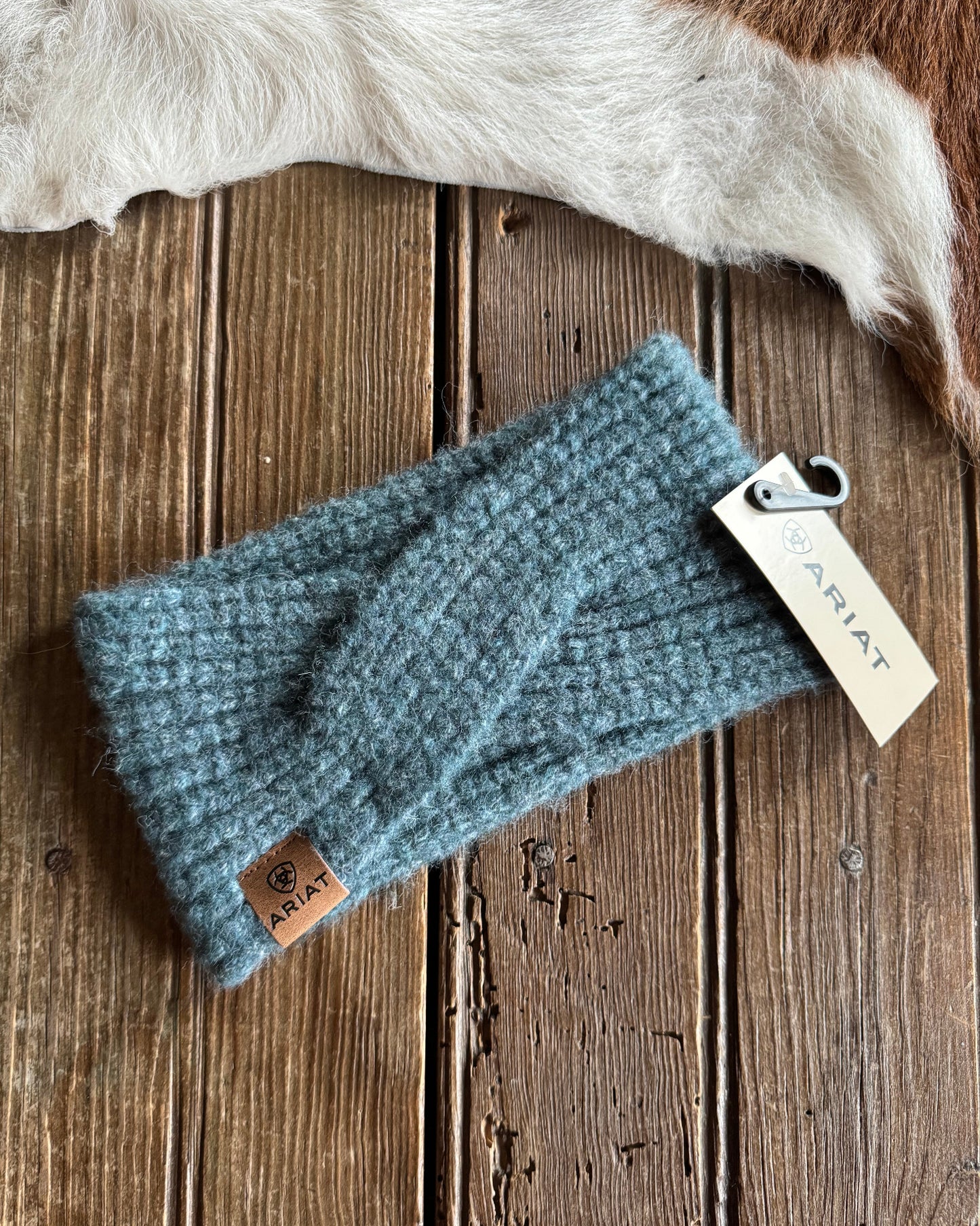 Blue knitted headband with a brand tag on a wooden surface