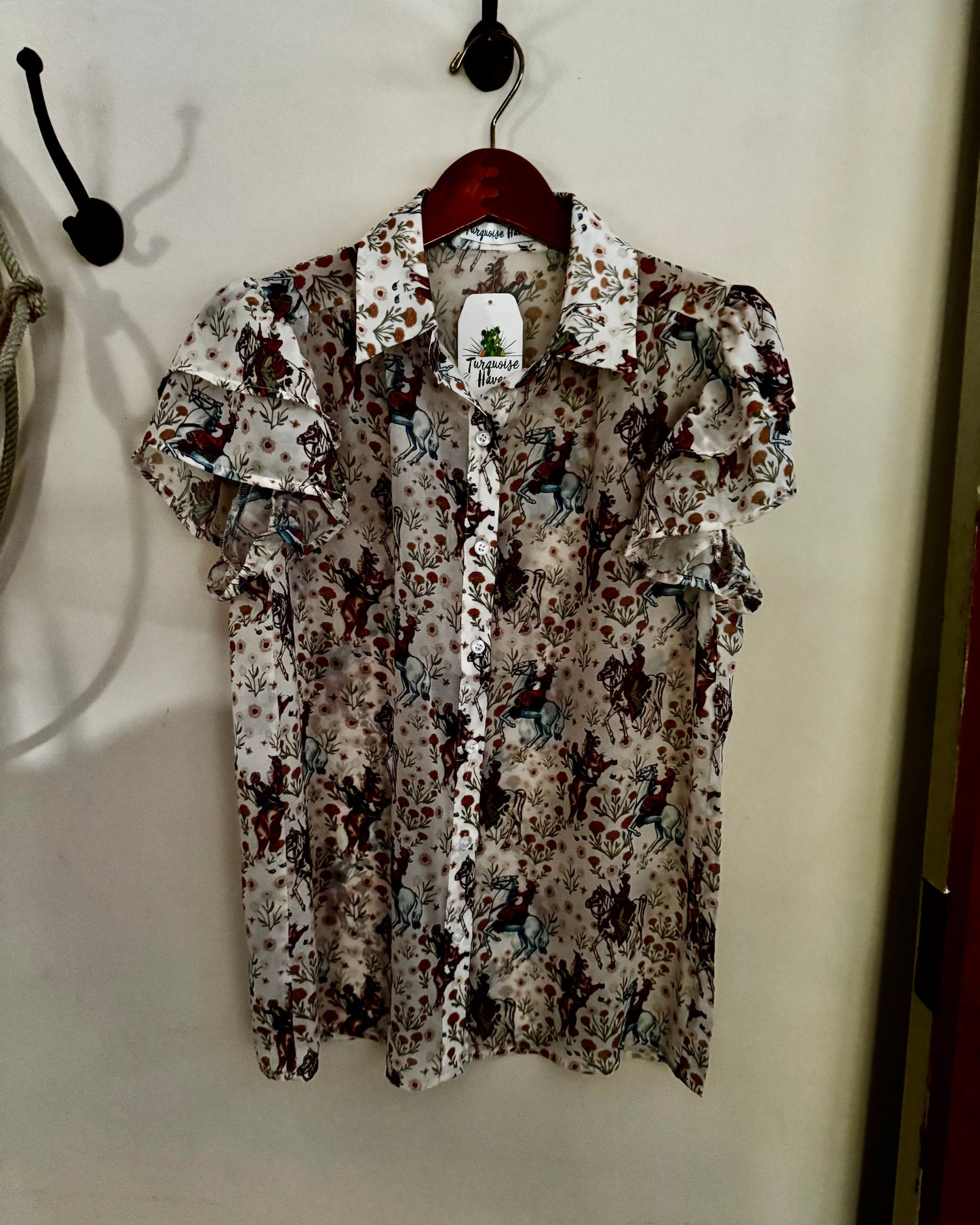 Floral patterned shirt on a hanger against a plain wall