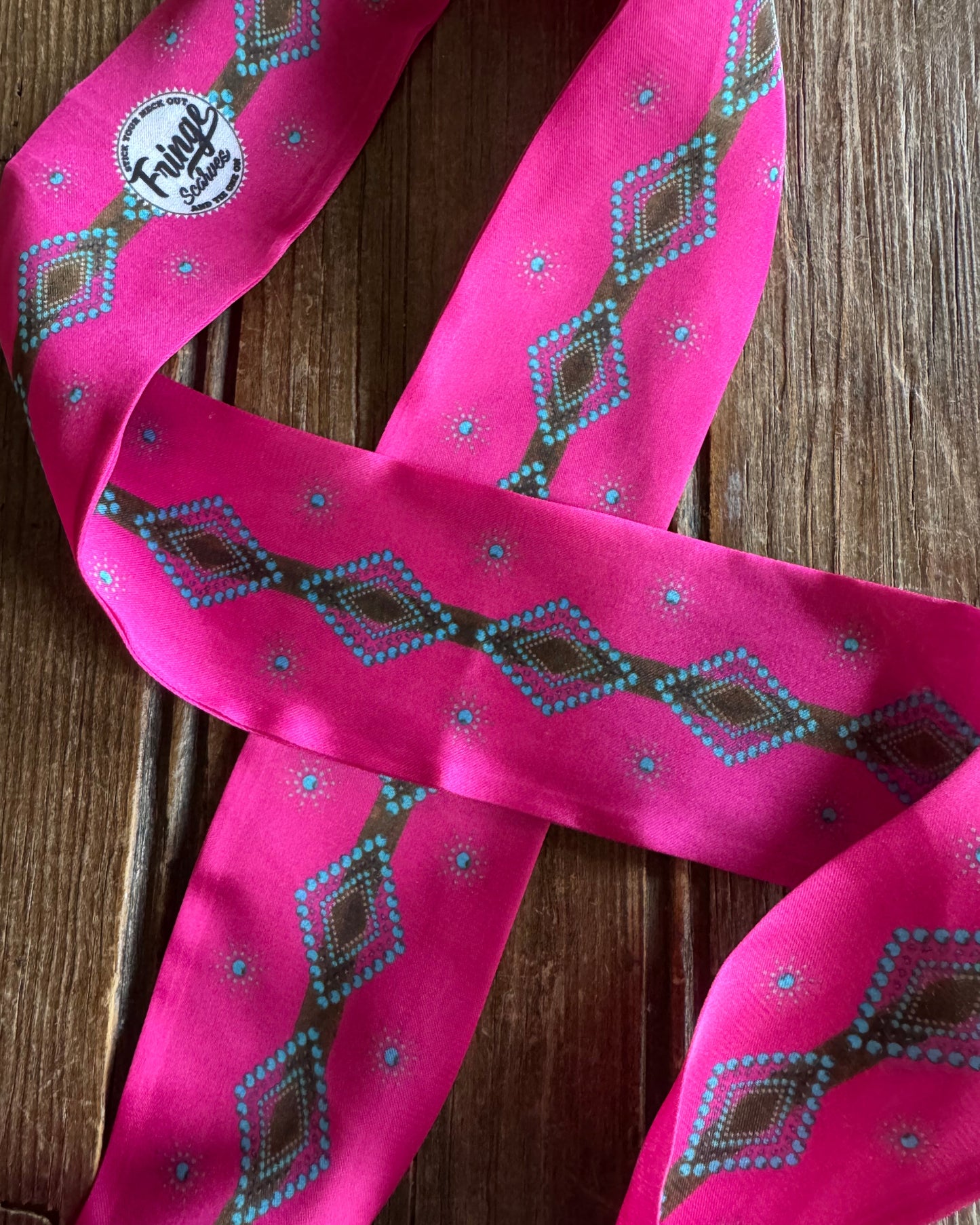 Pink ribbon scarf with geometric pattern on a wooden surface