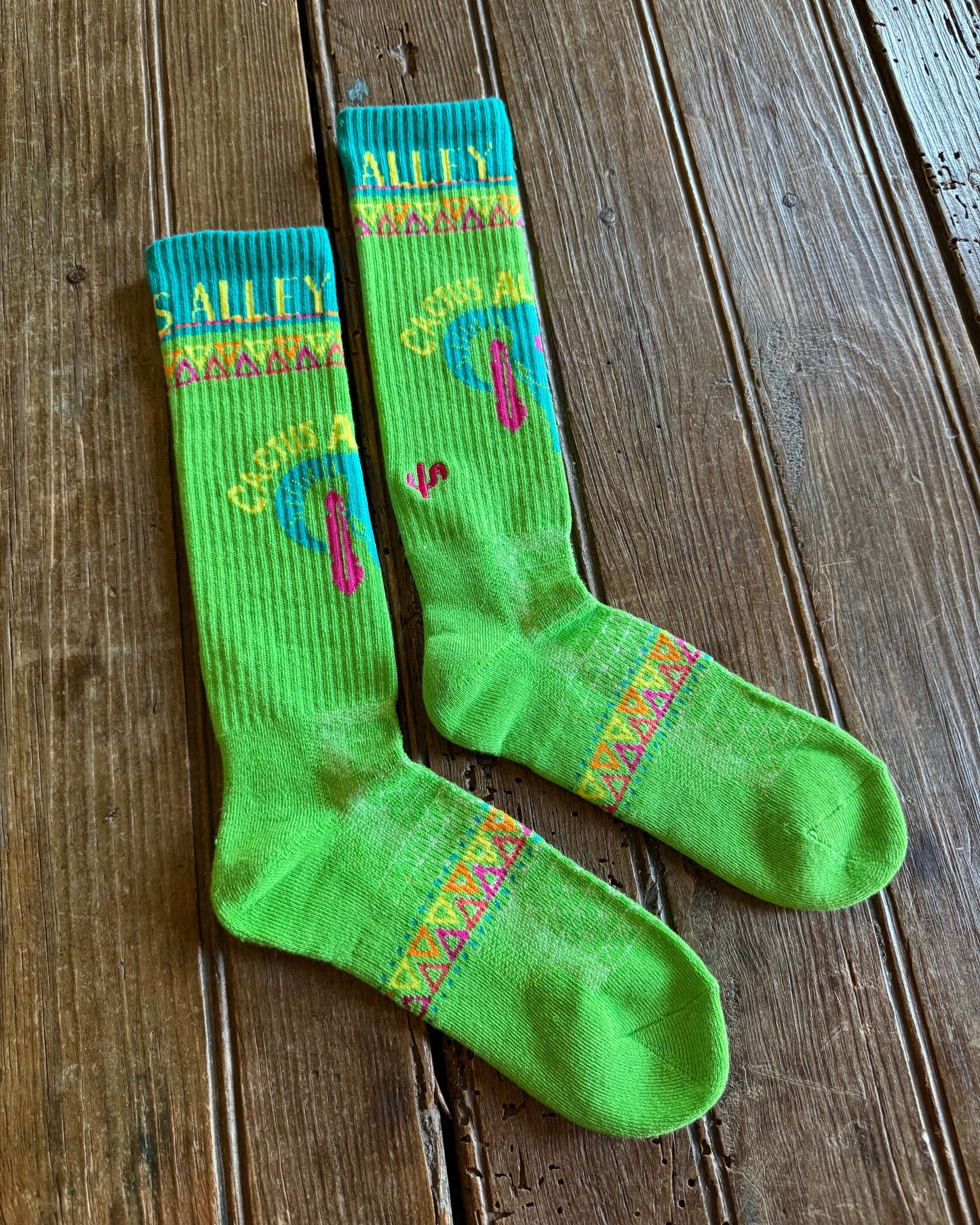 Cactus Alley Southwest Green Performance Socks on rustic wood background