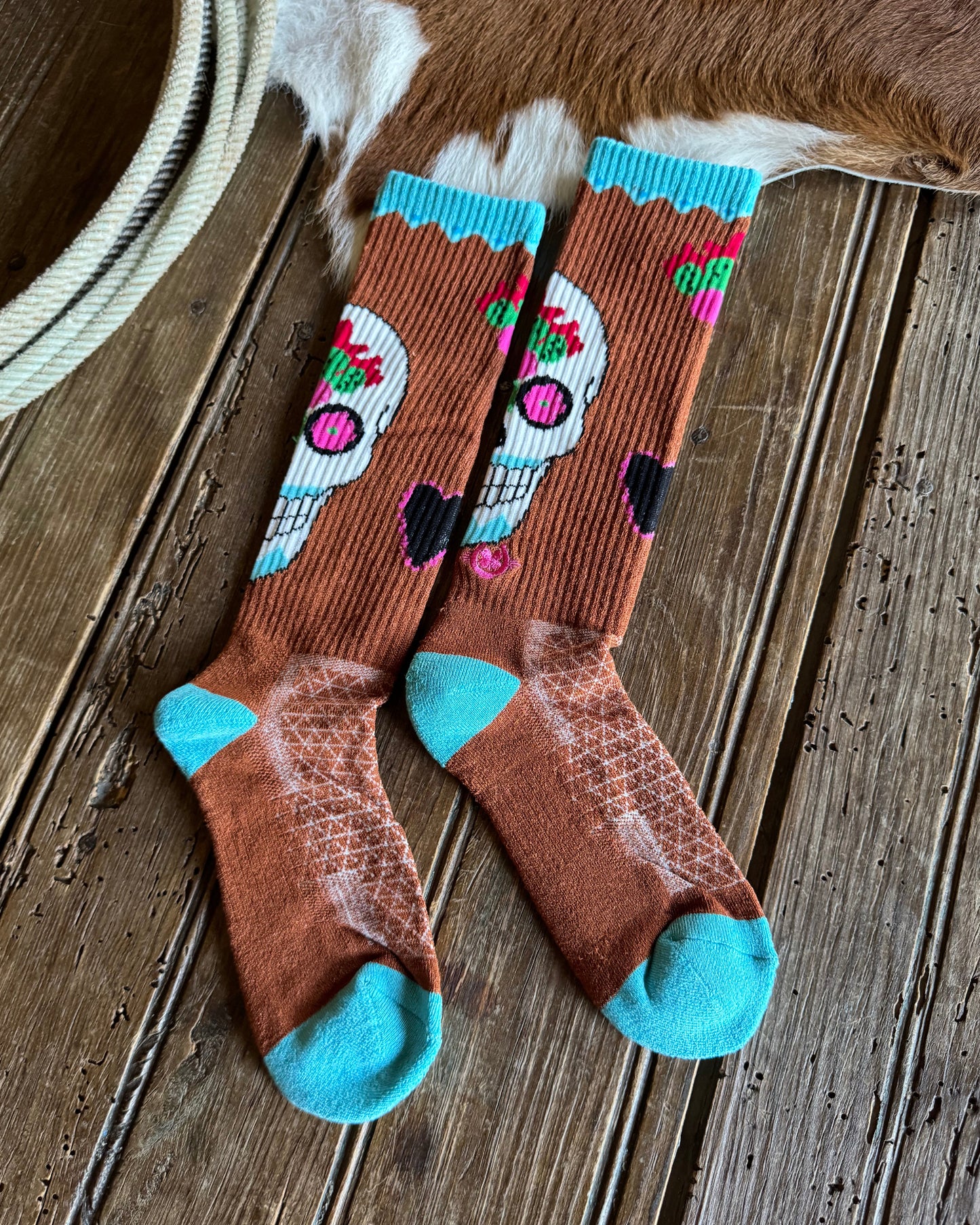 Pair of brown socks with colorful designs on a wooden surface
