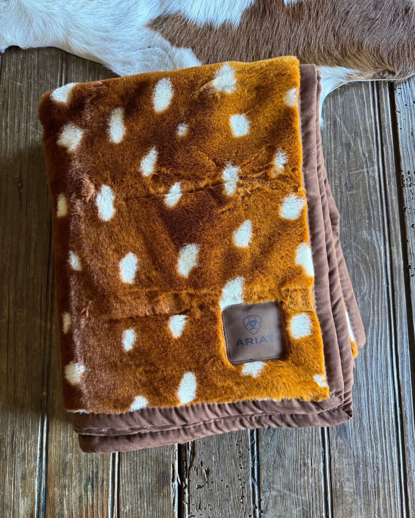 Folded brown blanket with white spots on a wooden surface