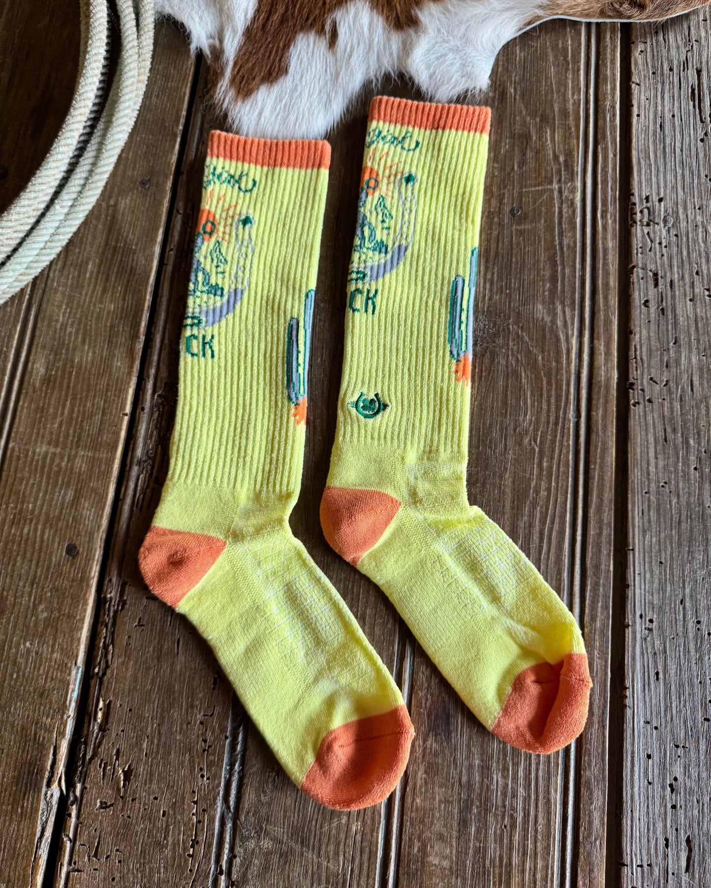 Pair of yellow socks with colorful designs on a wooden surface.