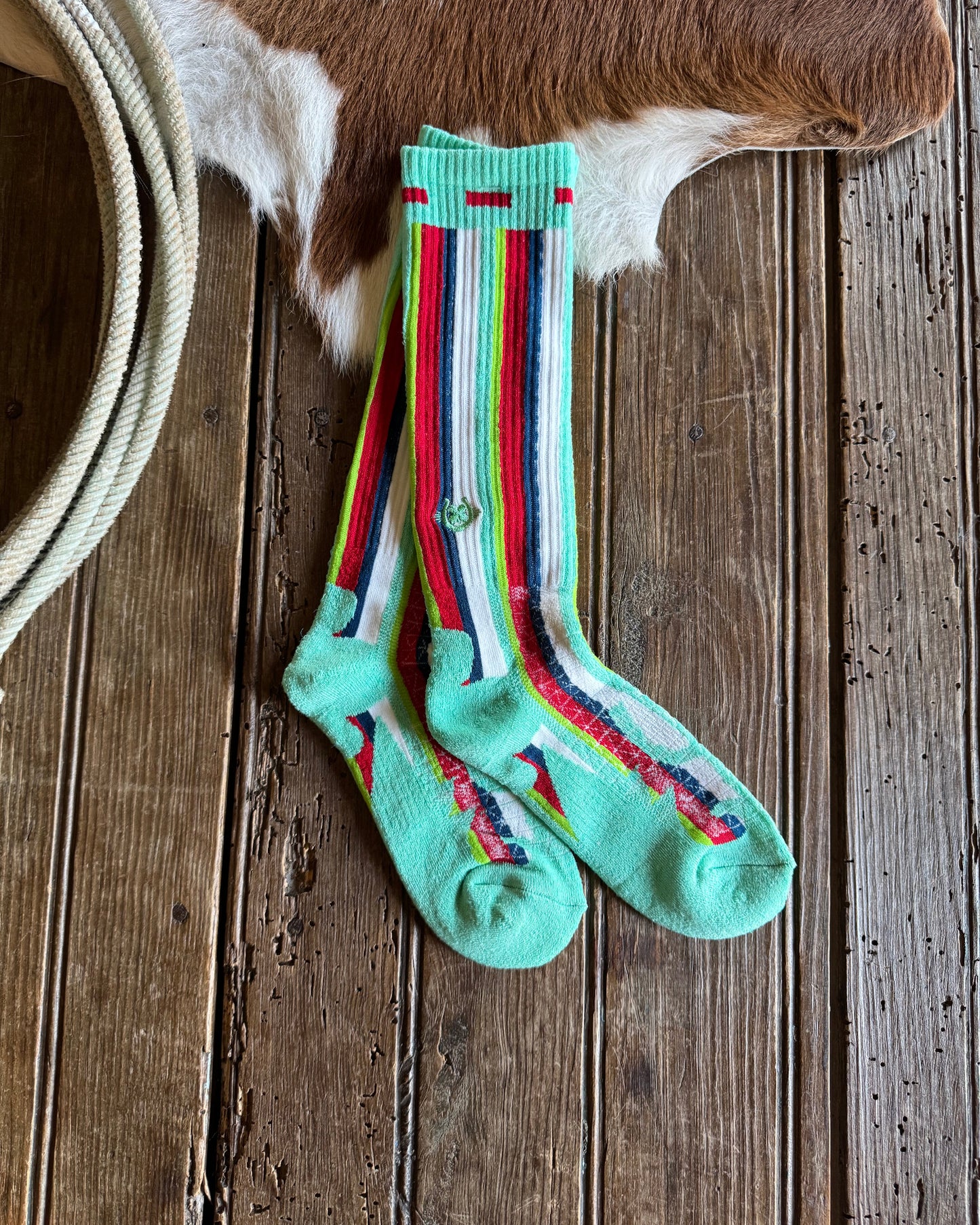 Pair of striped socks on a wooden surface with a cowhide