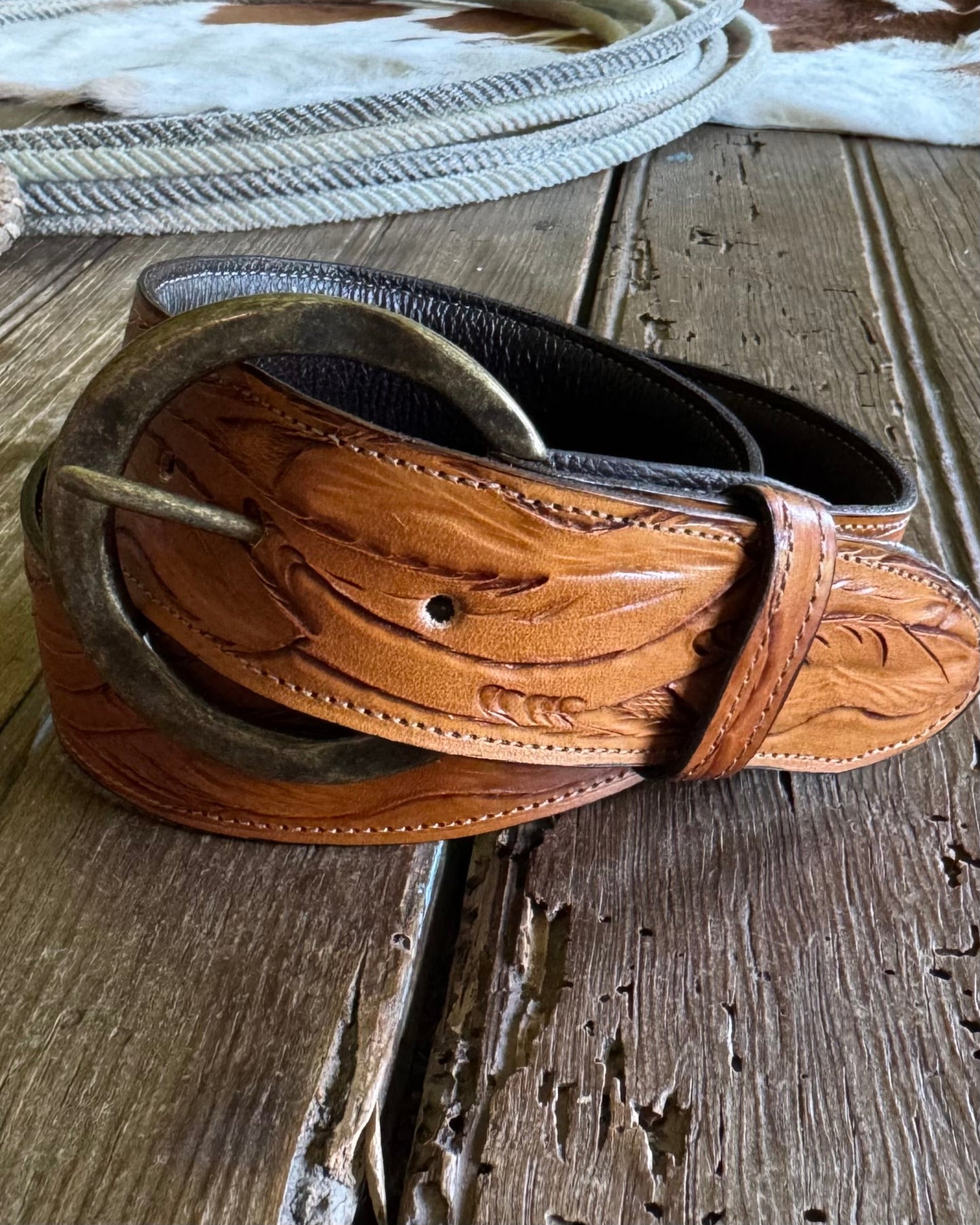 Brown leather belt with intricate designs on a wooden surface