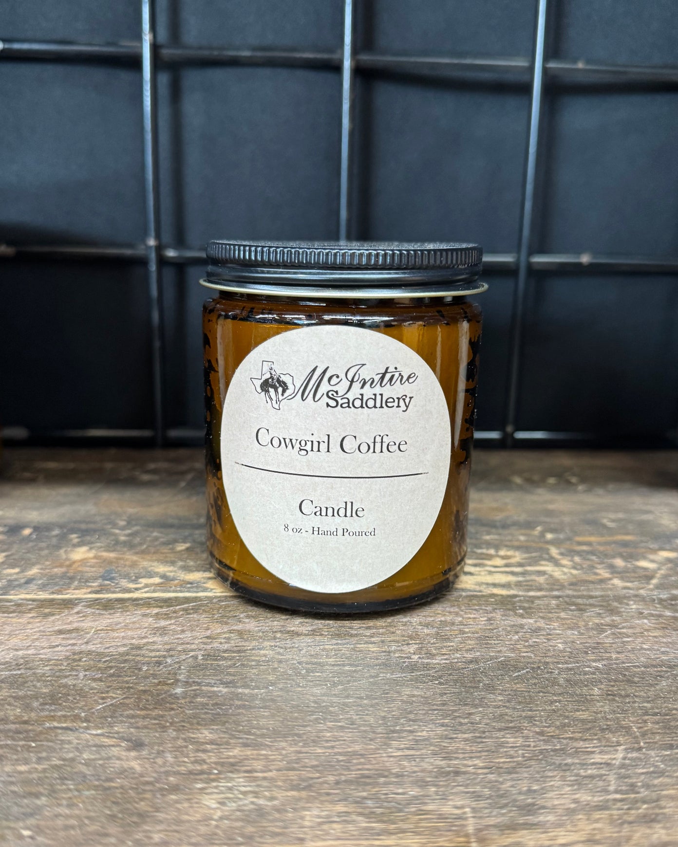 Cowgirl Coffee Candle on a wooden surface with a black grid background