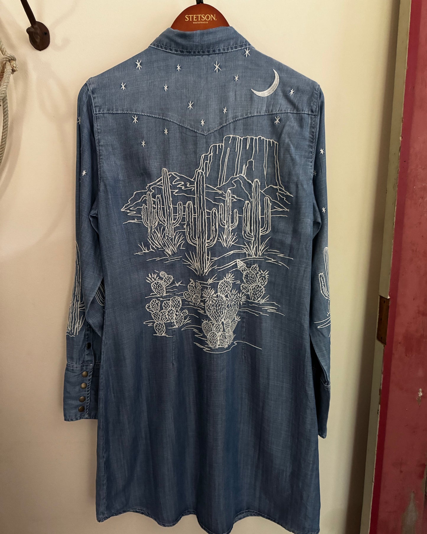 Blue denim shirt with white graphics on a beige wall