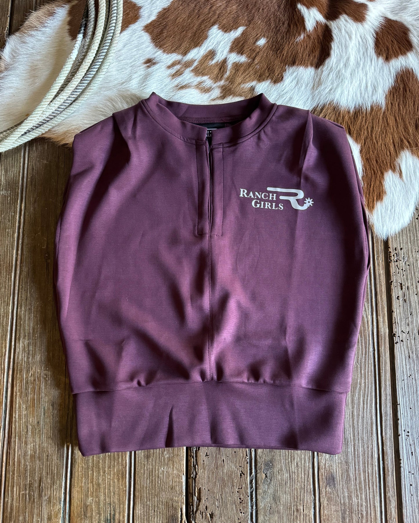 Purple shirt with 'Ranch Girls' logo on a wooden surface with cowhide rug