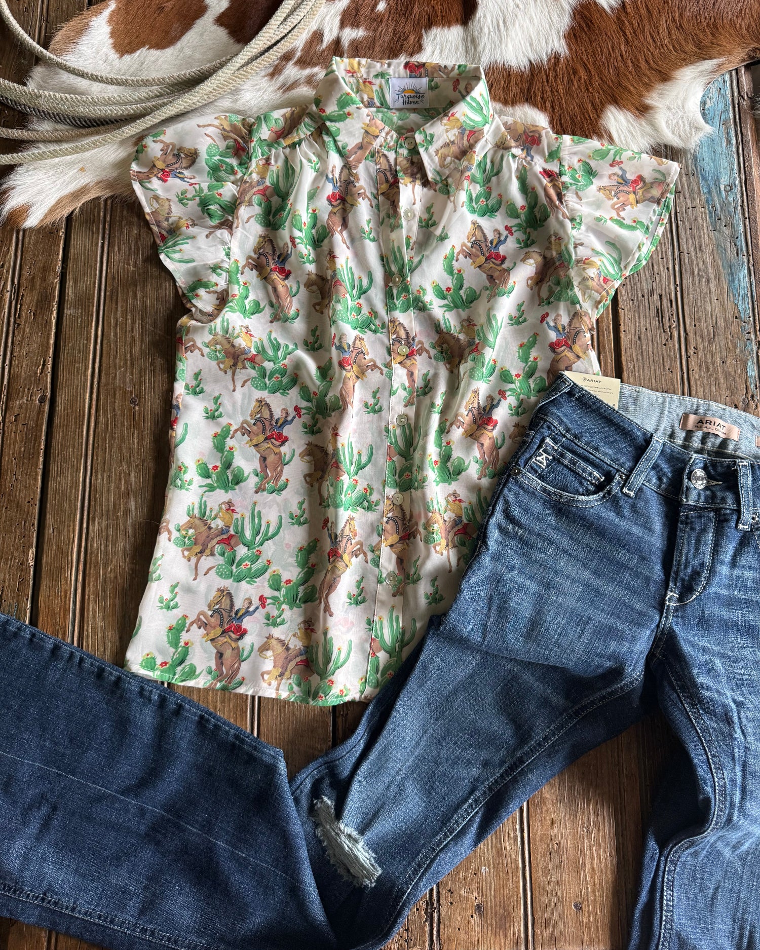 Floral shirt and blue jeans on a wooden surface with cowhide rug