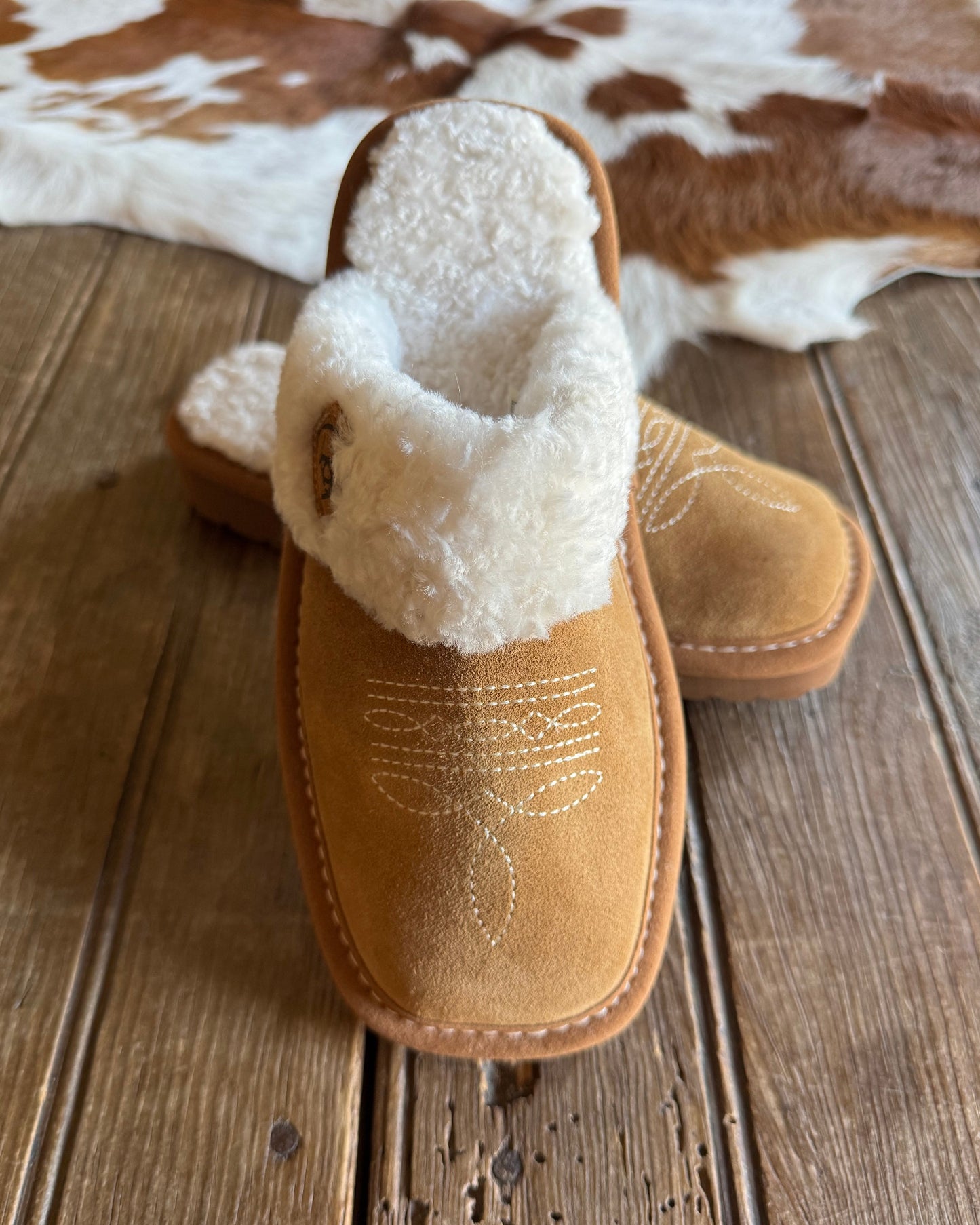 Brown slipper with white fur lining on a wooden surface
