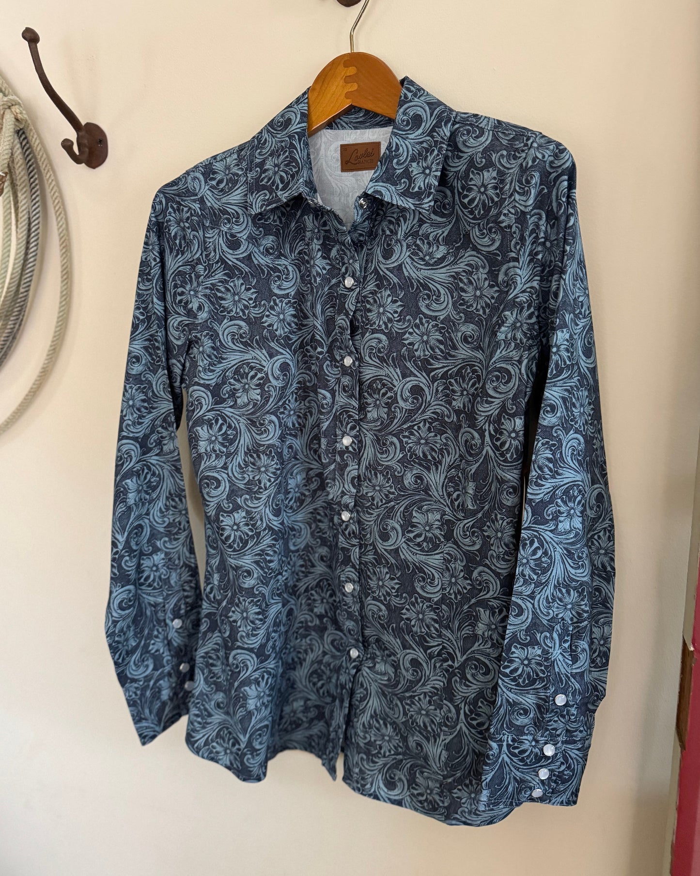 Blue patterned shirt on a hanger against a white wall