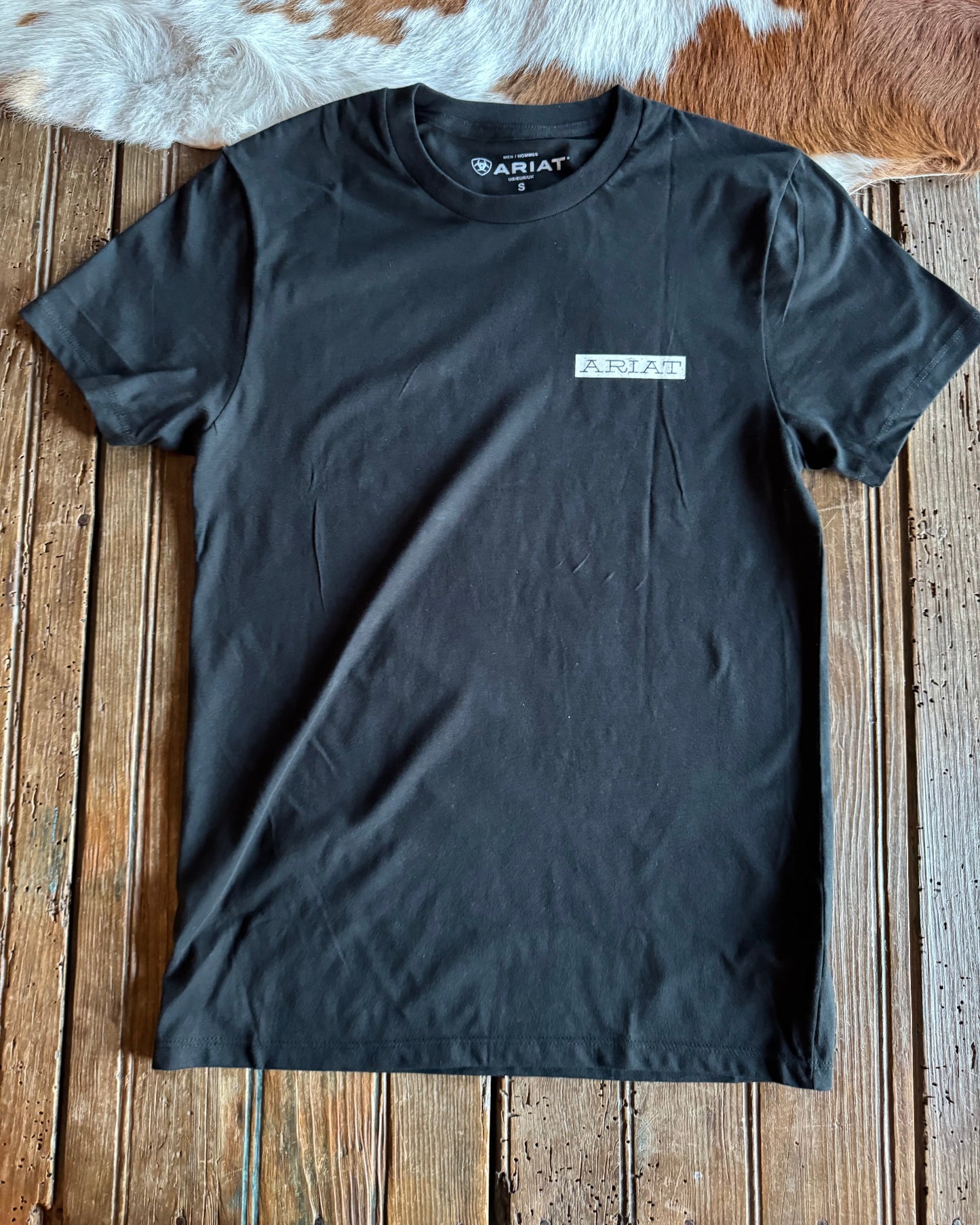 Black t-shirt with a brand logo on a wooden surface