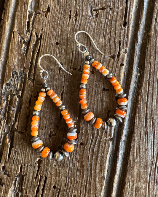 Orange spiny loop earrings with sterling silver pearls on rustic wood background