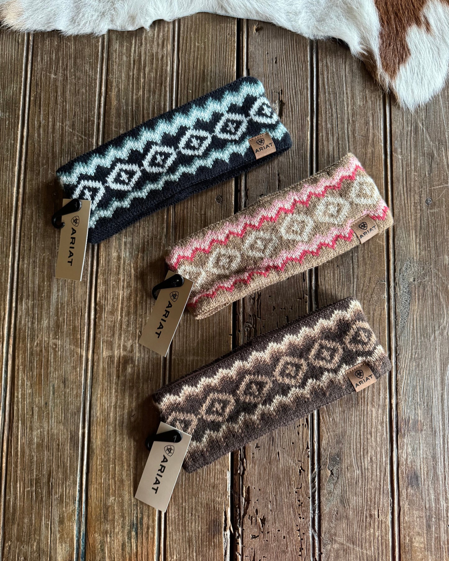 Three patterned headbands on a wooden surface with visible brand tags.