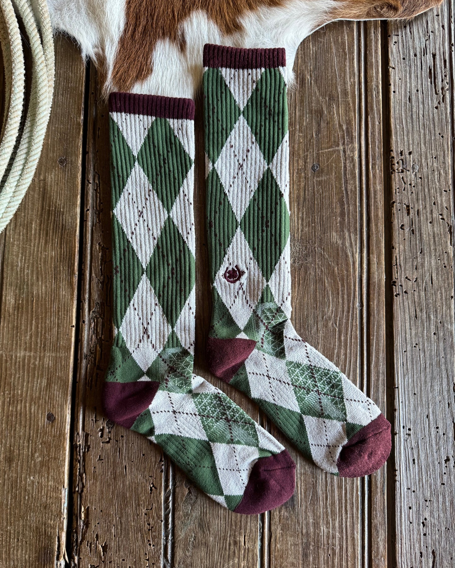 Green and white checkered sock with maroon accents on a wooden surface
