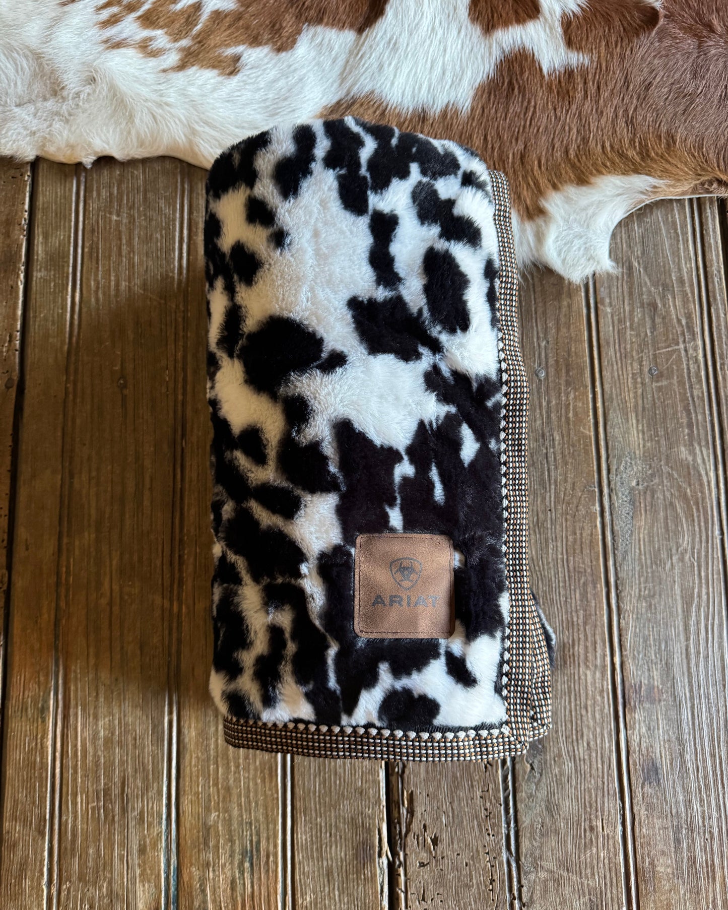 cow print blanket on a wooden surface with cowhide rug