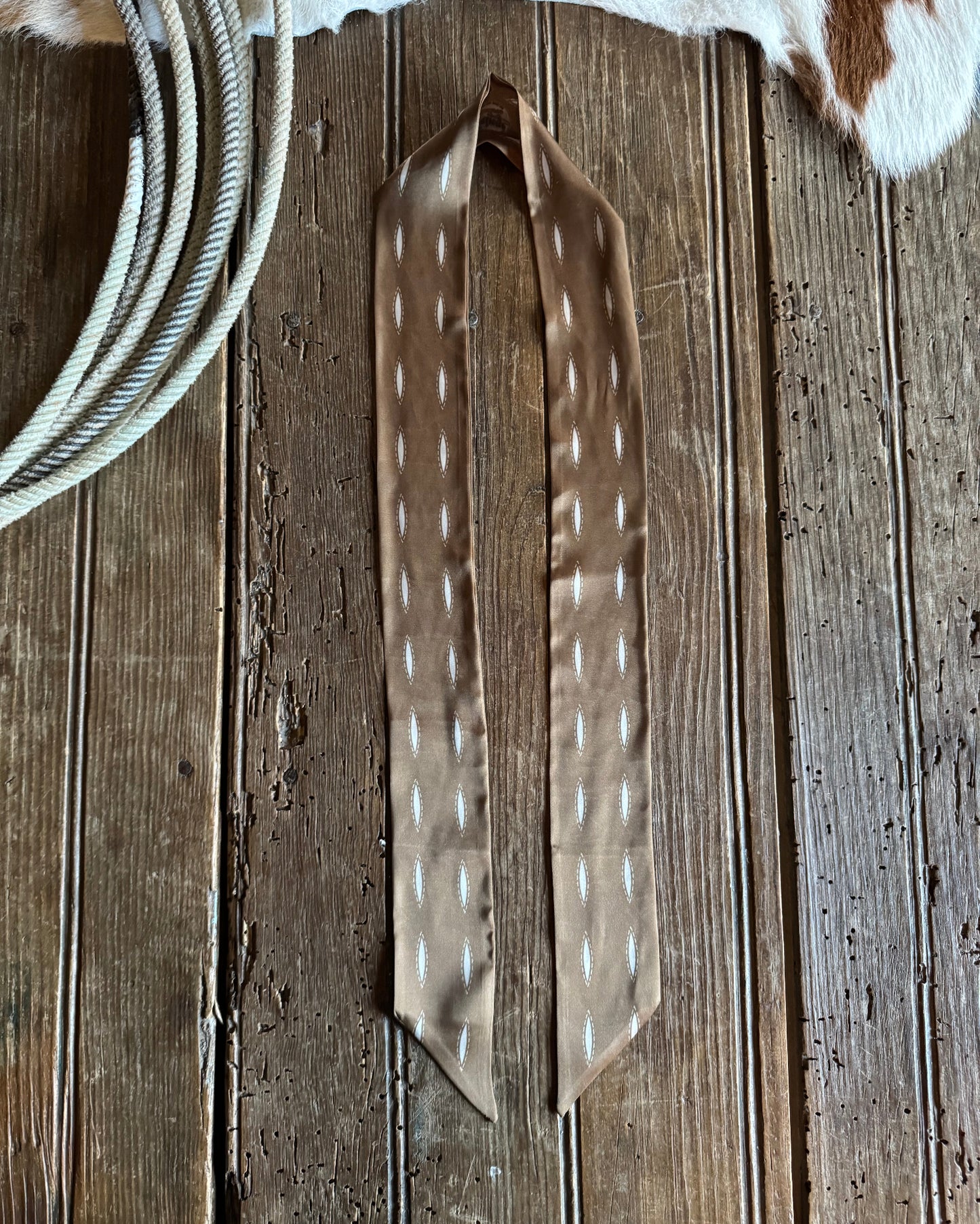 Ribbon scarf with white patterns on a wooden surface.