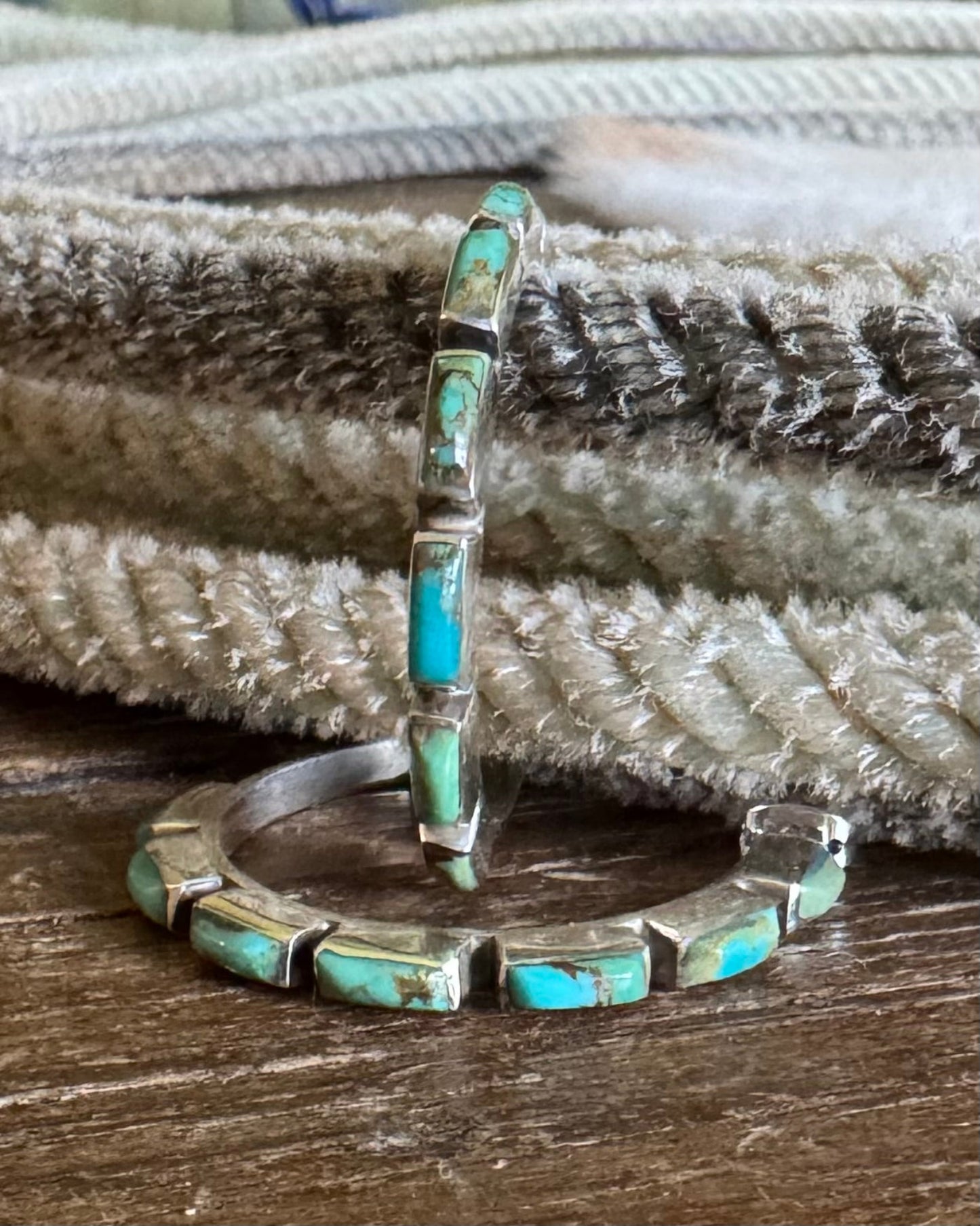 Turquoise inlay silver earrings on a textured surface