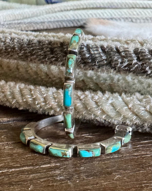 Turquoise inlay silver earrings on a textured surface