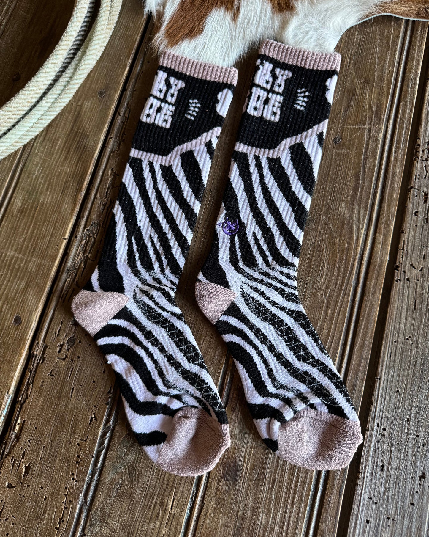 Pair of zebra-striped socks with pink accents on a wooden surface.