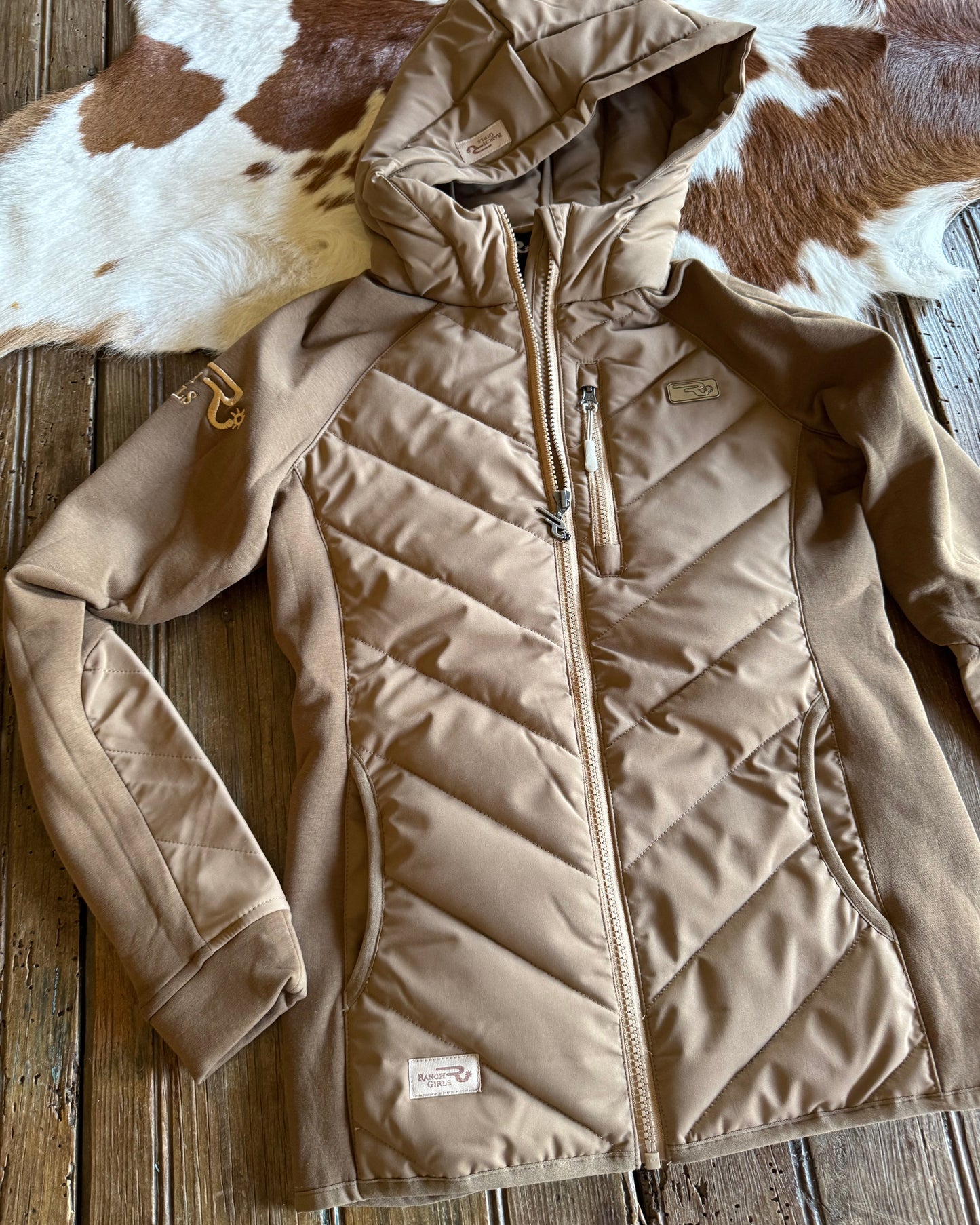 Beige quilted jacket on a wooden surface with a cowhide rug