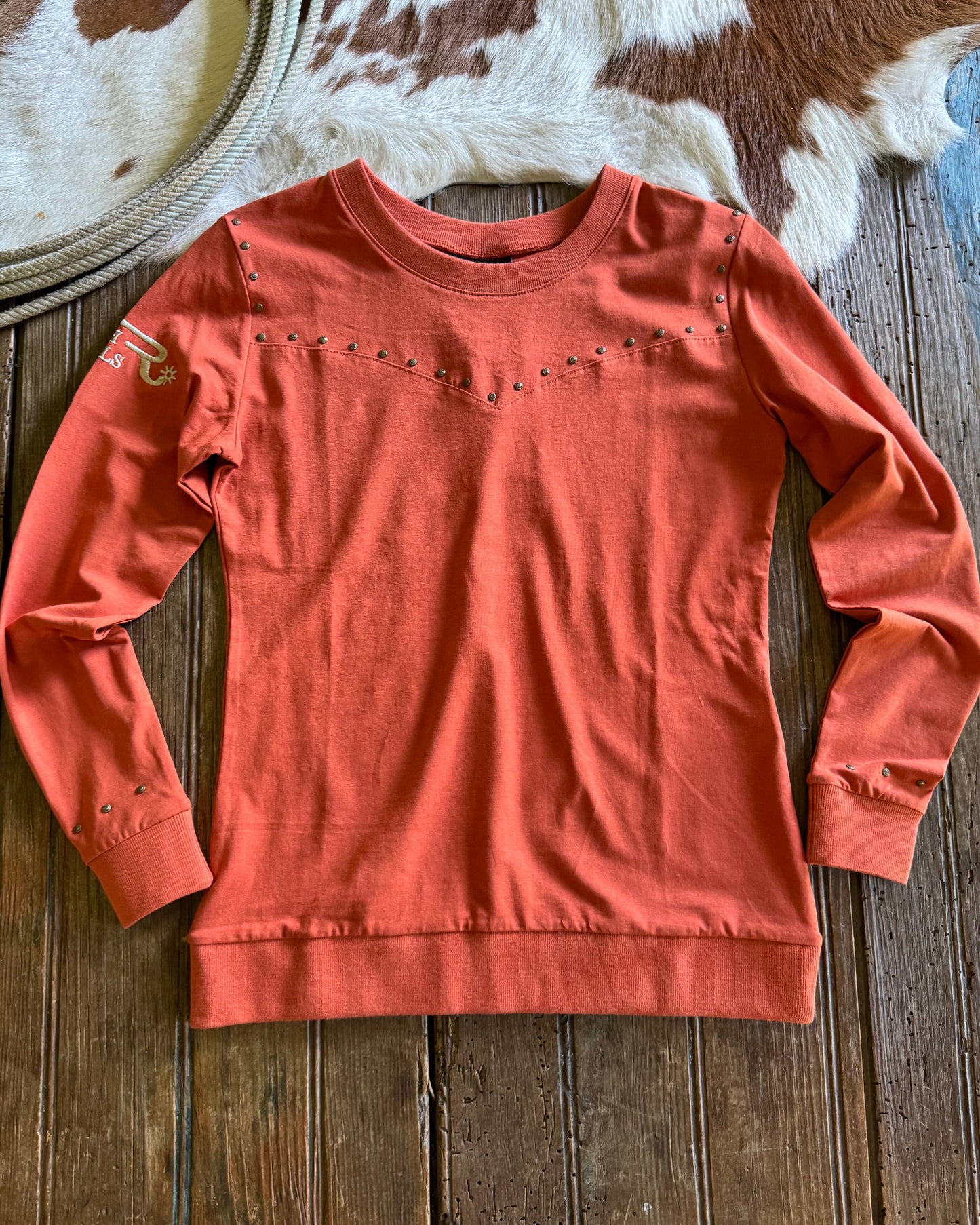 Coral-colored shirt on a wooden surface with cowhide rug