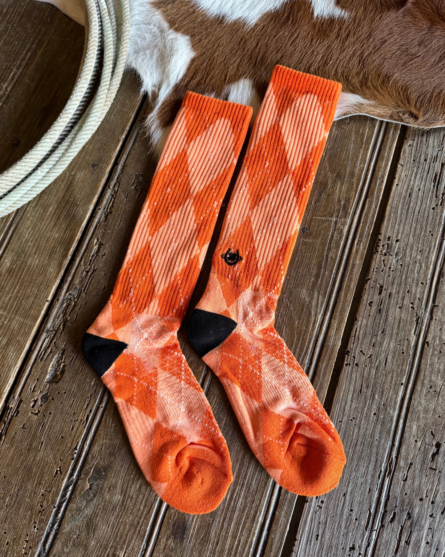 Pair of orange socks with black accents on a wooden surface