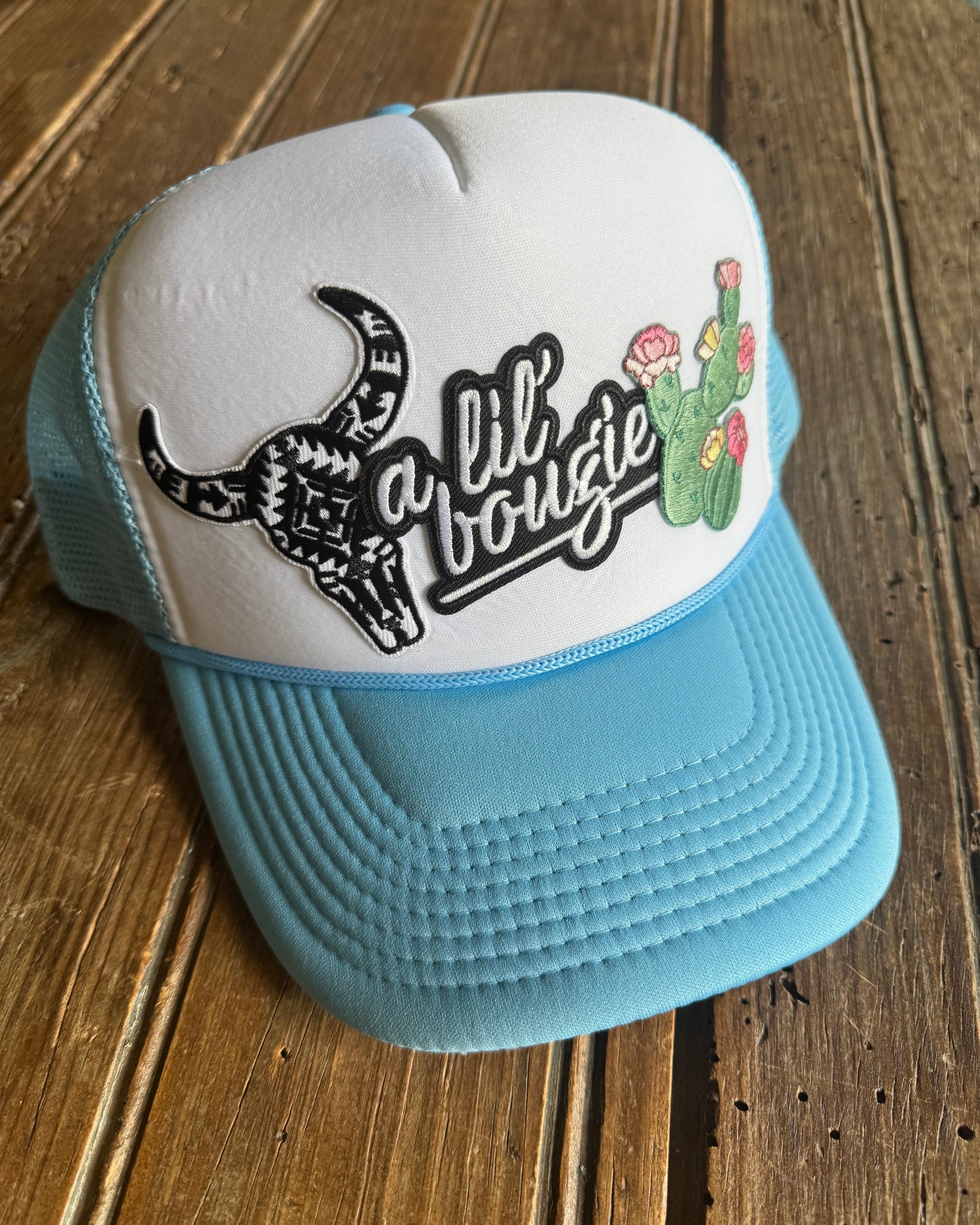 Light blue and white cap with a logo on a wooden surface