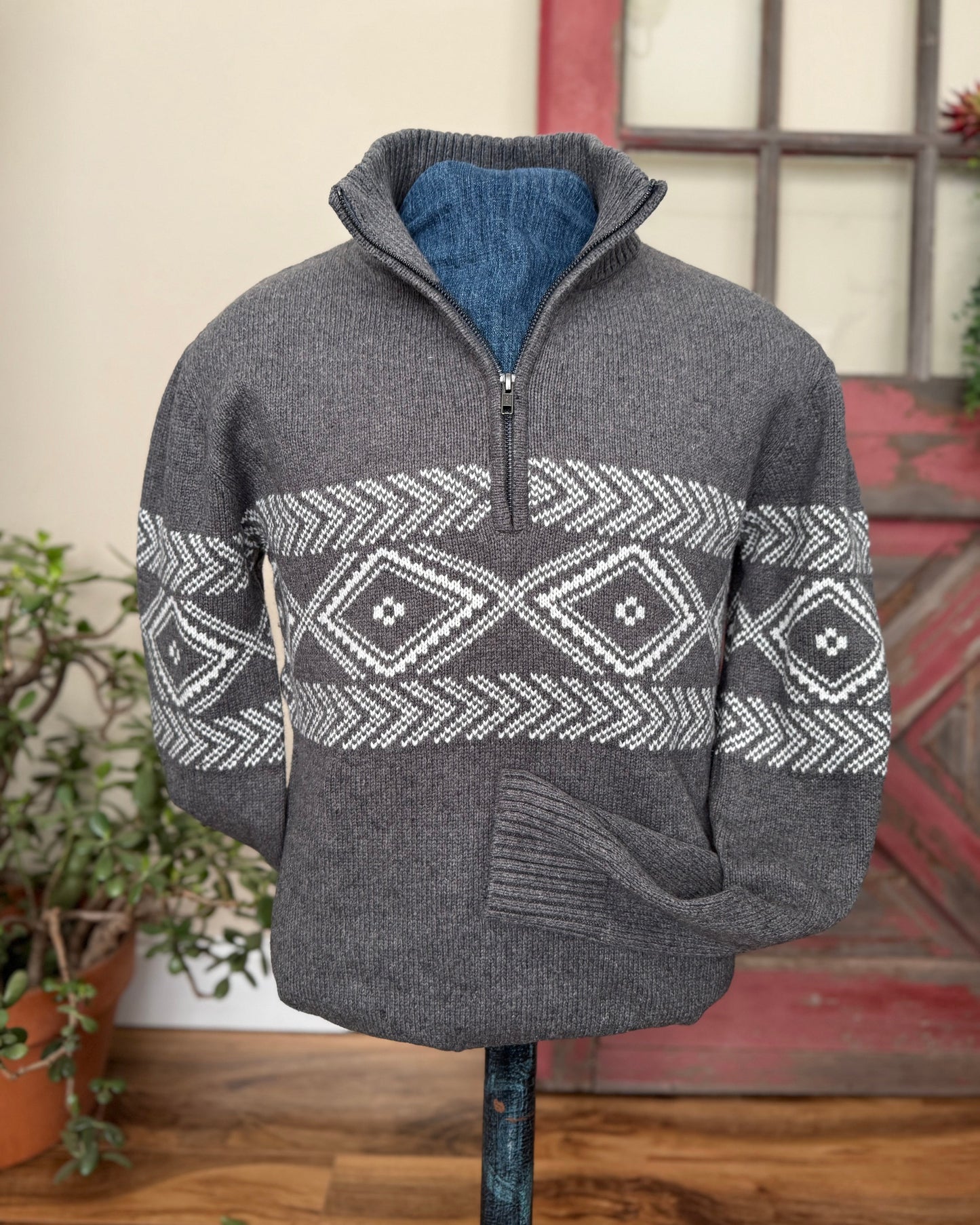 Gray sweater with a patterned design on a mannequin against a neutral background