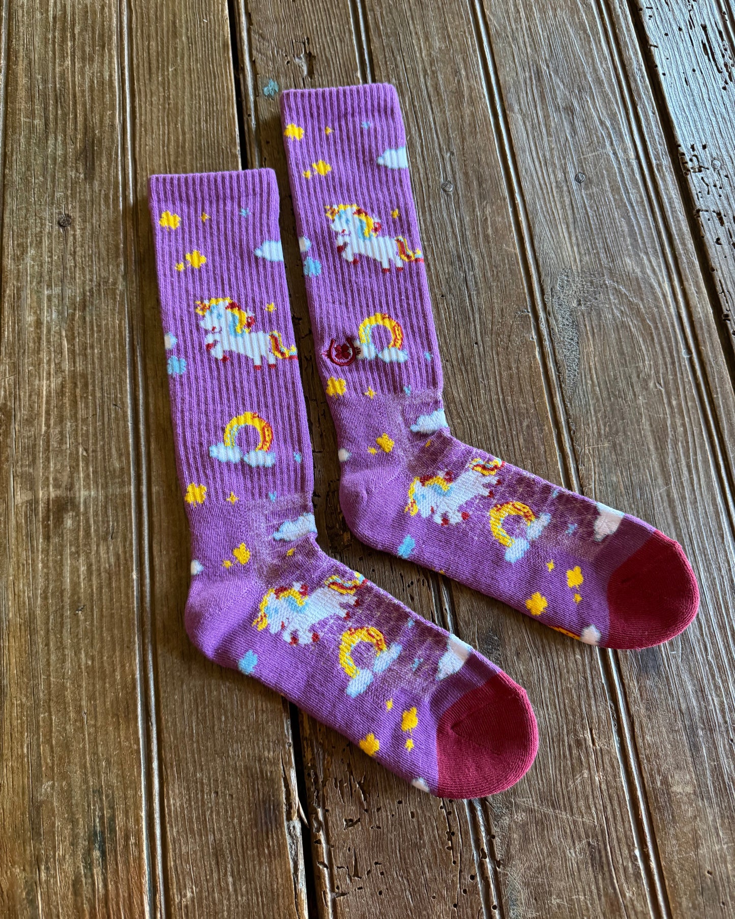 Lucky Unicorns Performance Socks in purple on rustic wood background