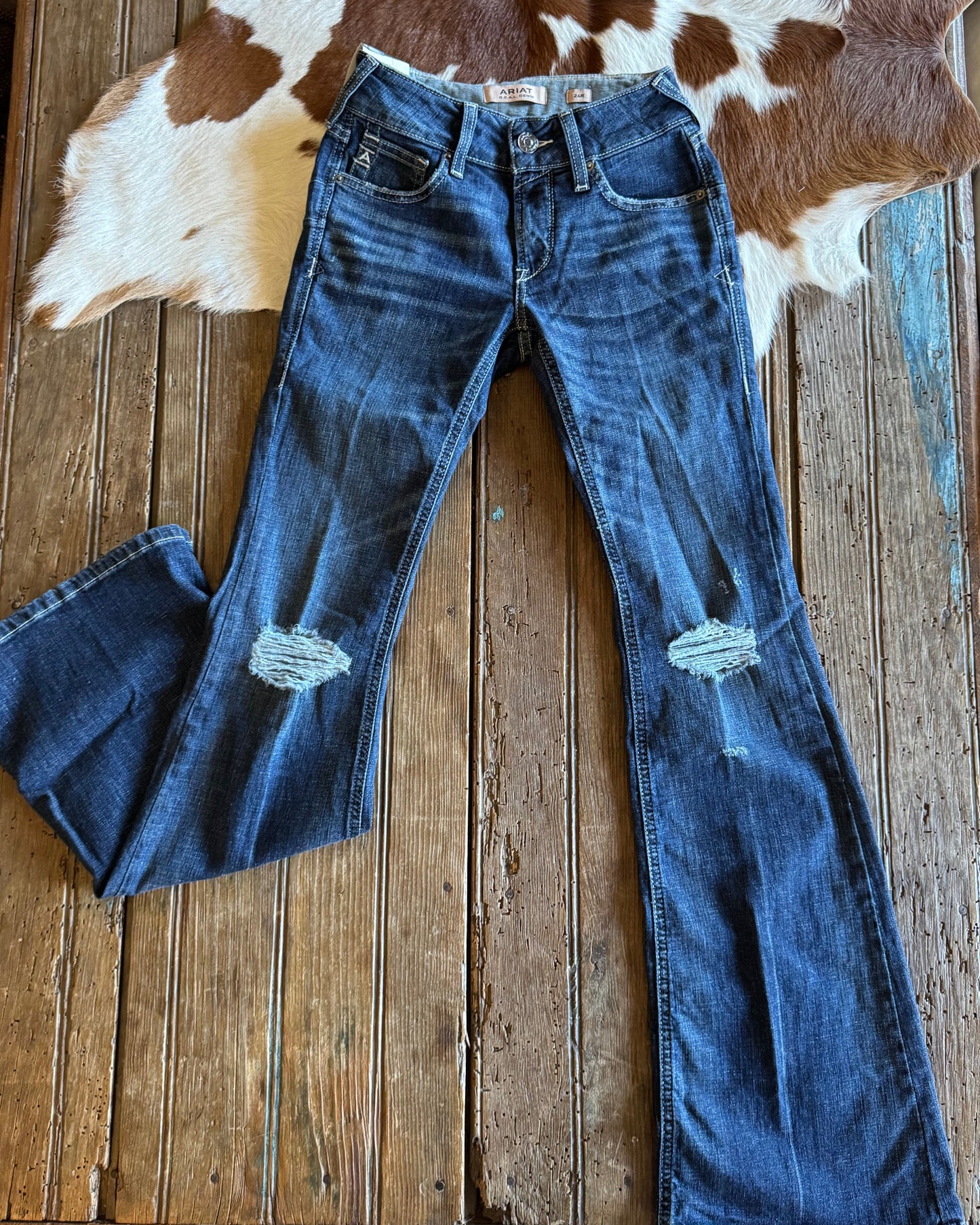 Front of distressed flare jeans on rustic wood background