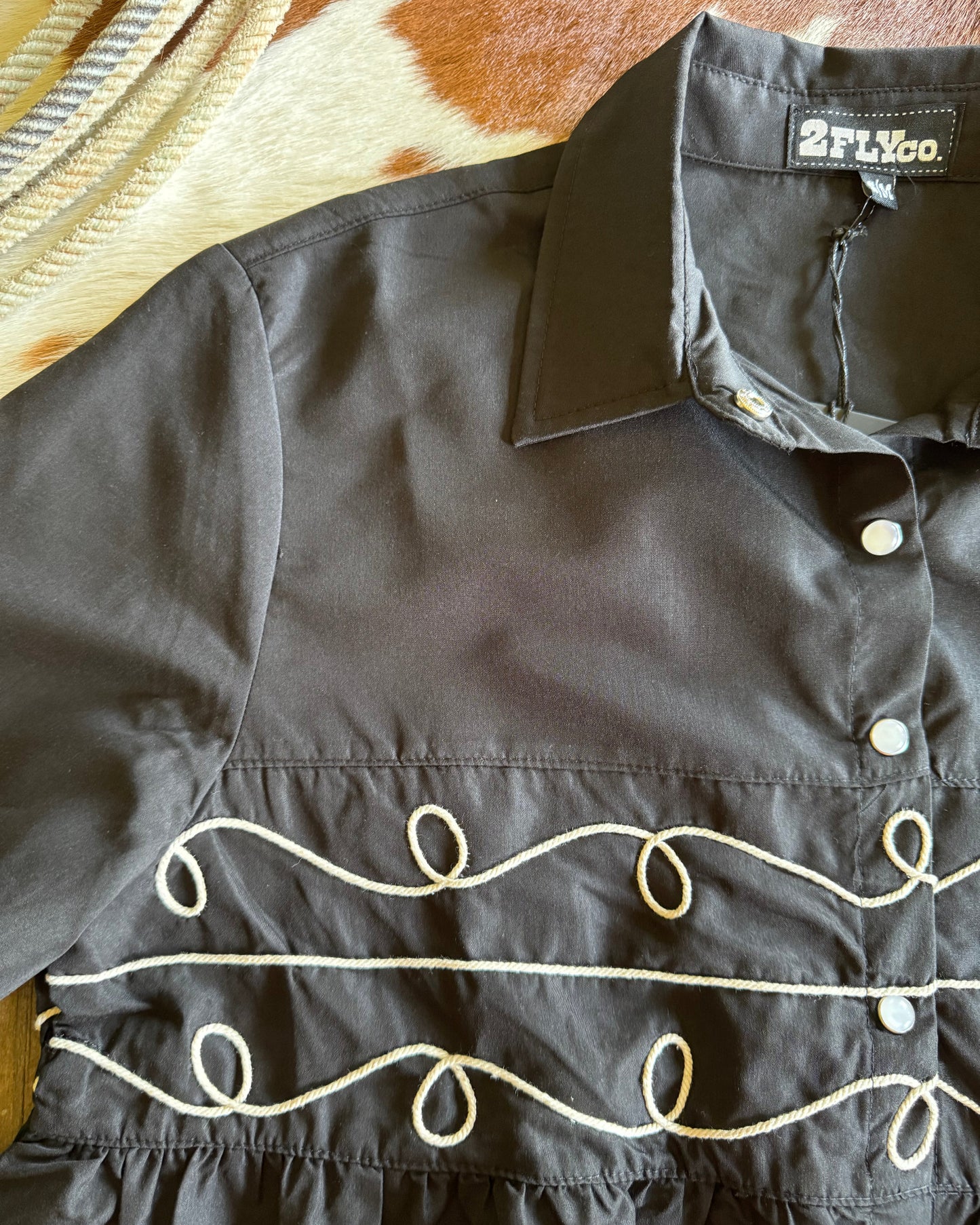 Close-up of a dark shirt with decorative buttons on a textured surface