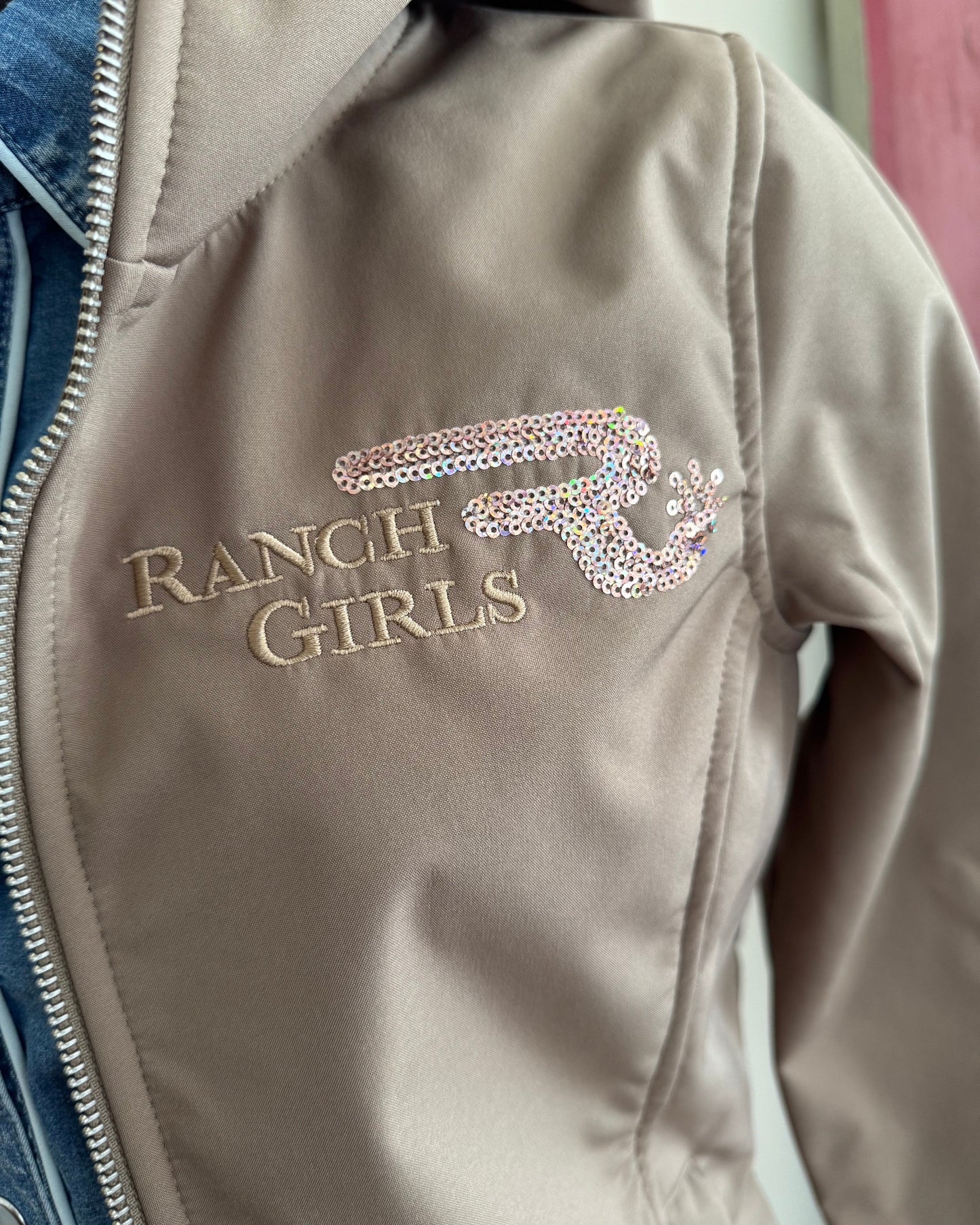 Beige jacket with 'Ranch Girls' and design on a blurred background