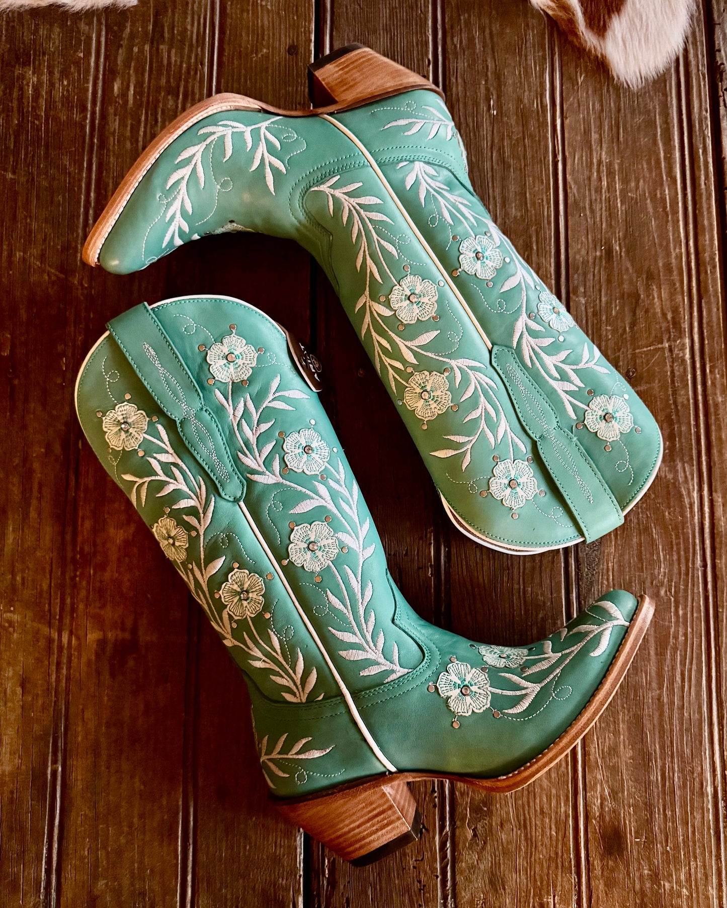 Turquoise Ariat Romance Embroidered Leather boots on rustic wood background