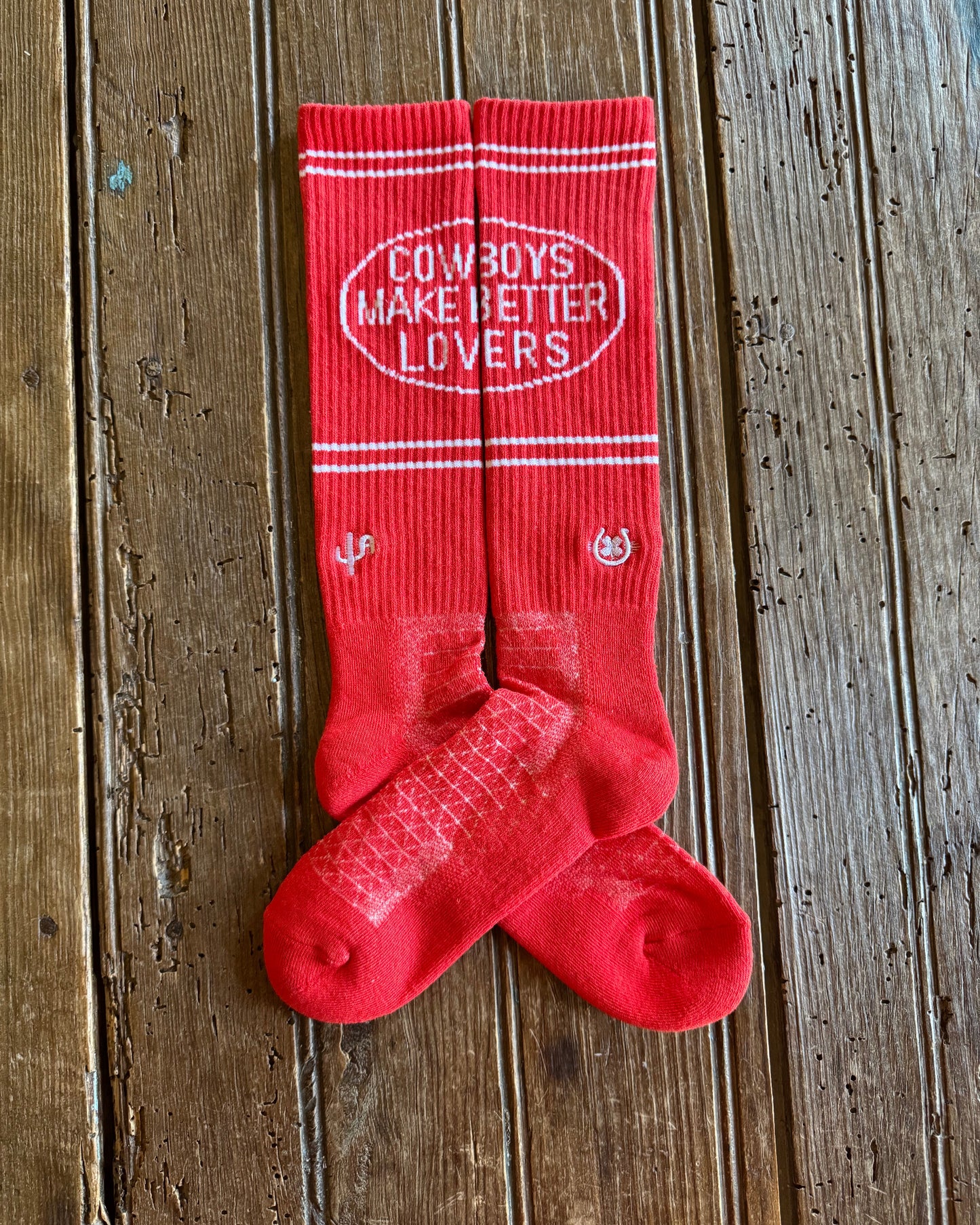 Cactus Alley Cowboy Lover Performance Socks in red showing design on rustic wood background