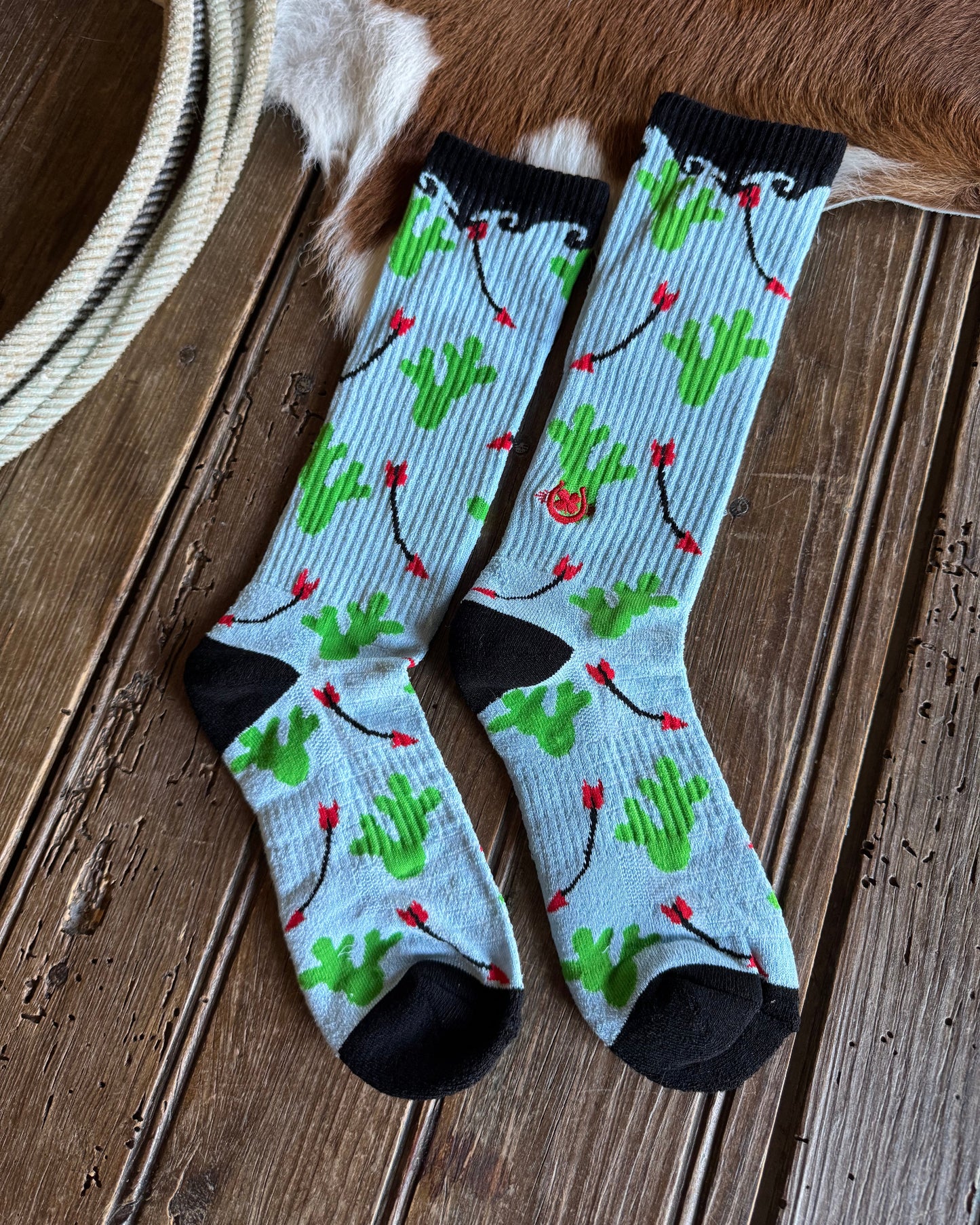 Pair of patterned socks on a wooden floor with a cowhide in the background.