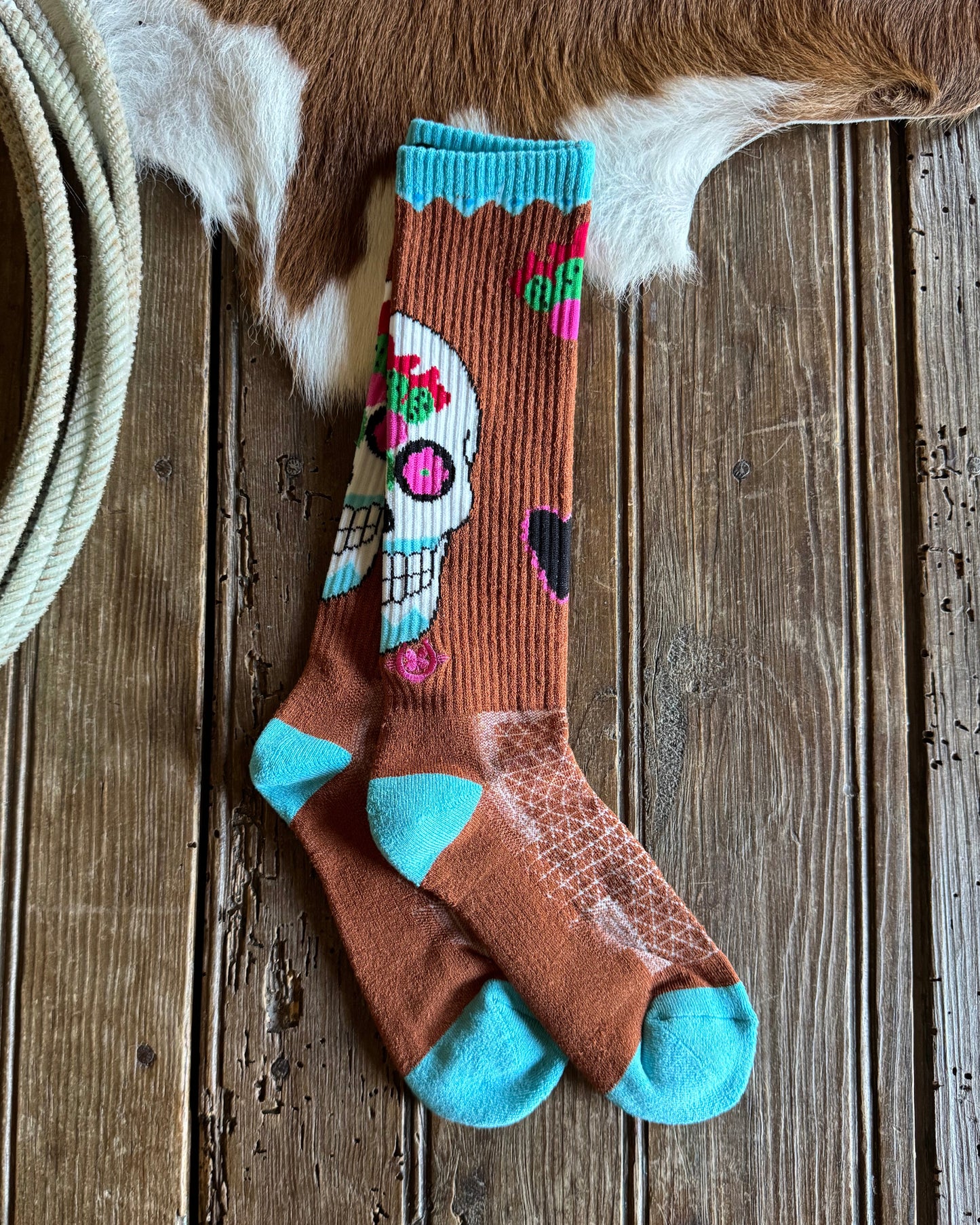 Sock with colorful design on a wooden surface next to a cowhide rug