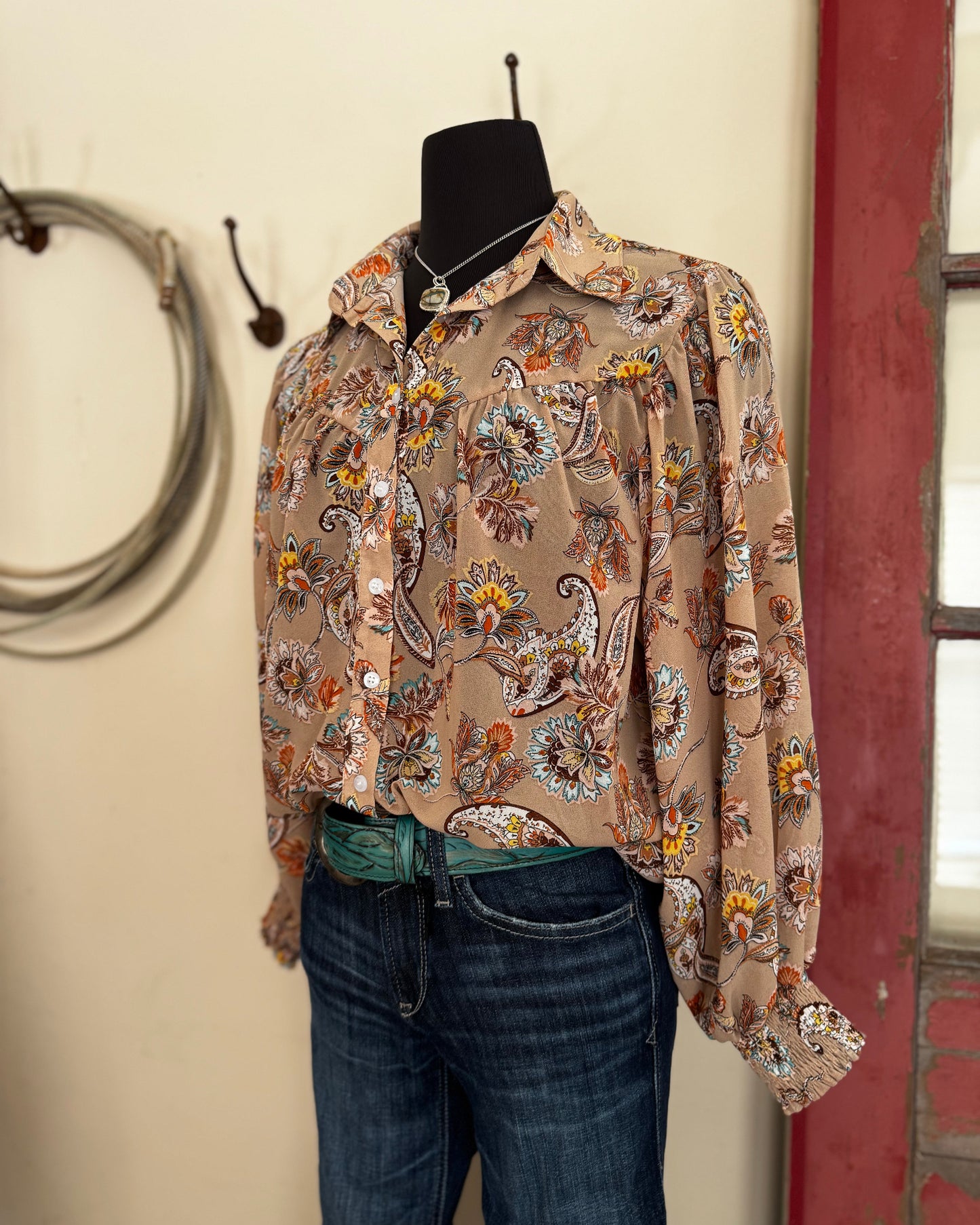 Floral patterned shirt on a mannequin with jeans against a neutral wall.
