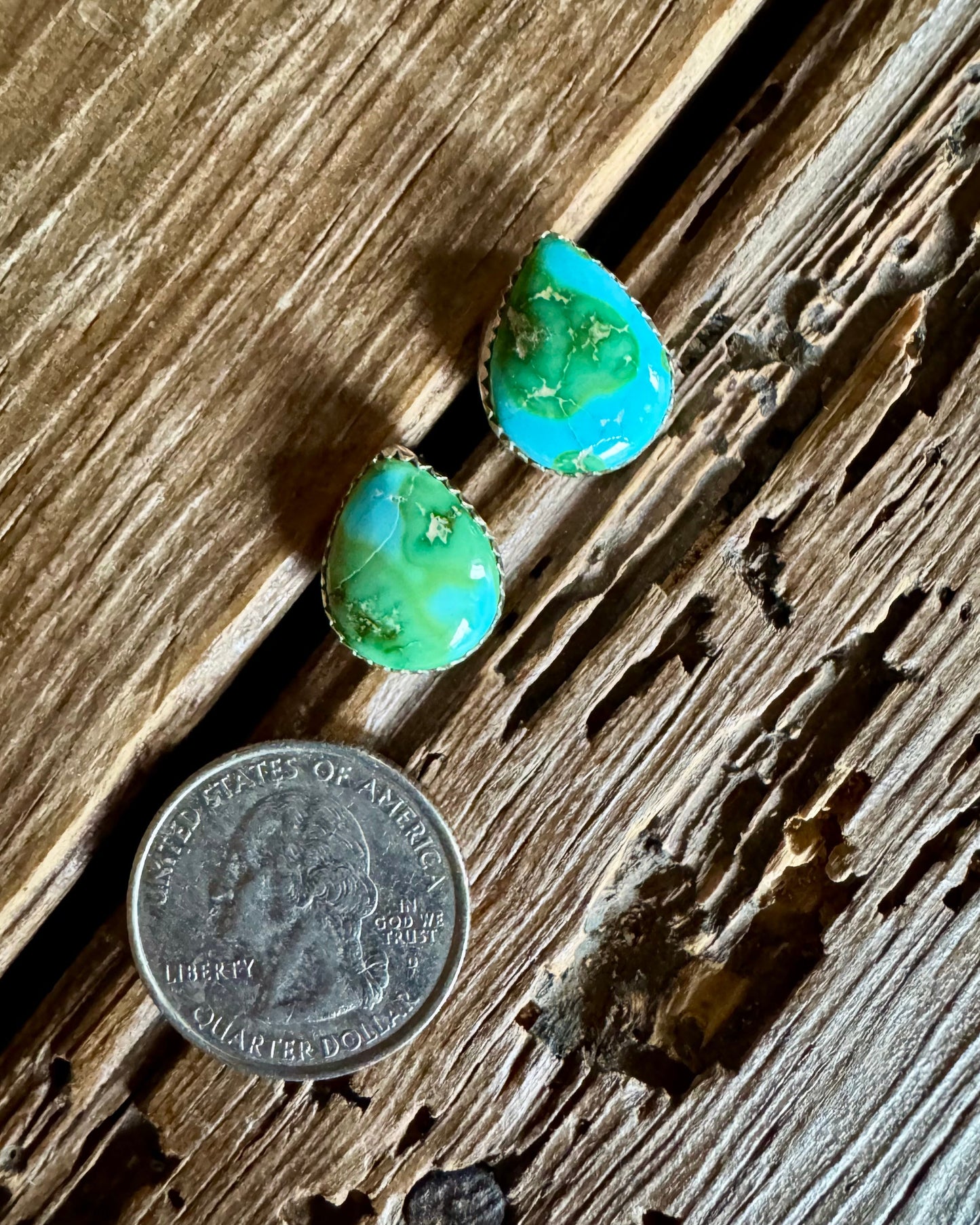 Turquoise earrings on a wooden surface with a quarter for scale.