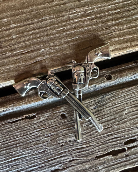 Silver revolver pin on a wooden background