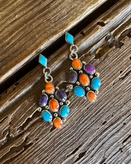 Sterling silver earrings with turquoise, orange and purple spiny stones on rustic wood background