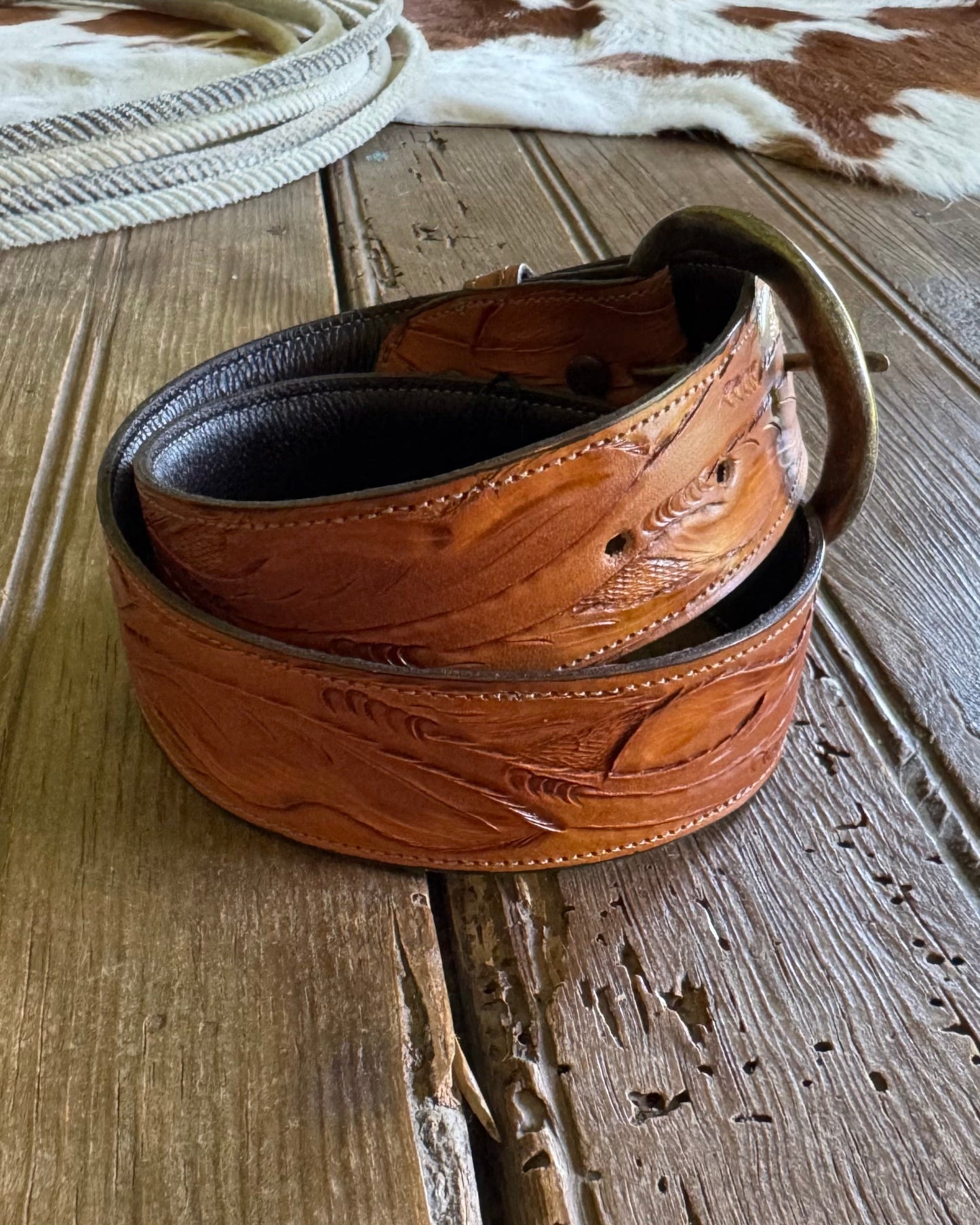 Brown leather belt with intricate designs on a wooden surface